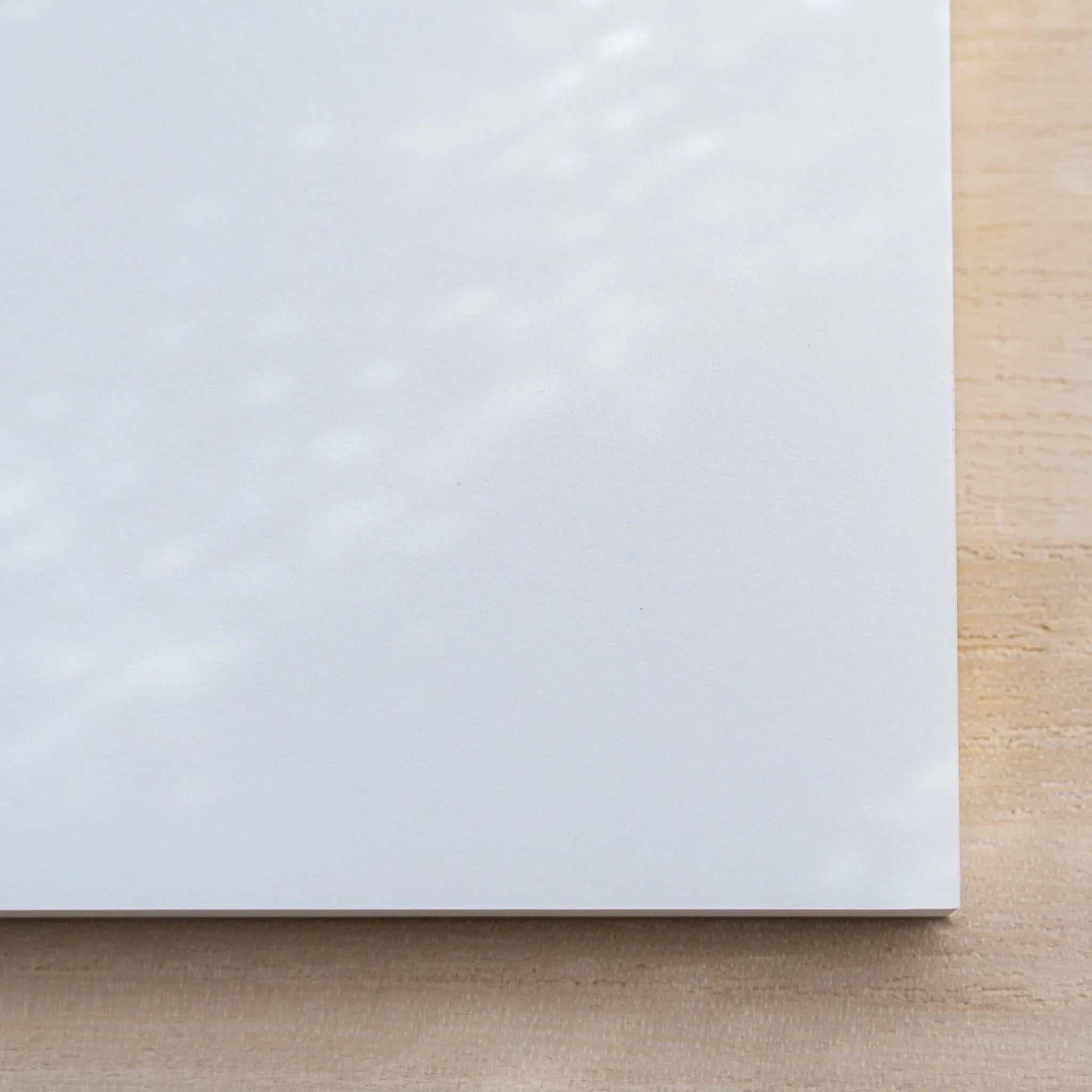 Close-up of Midori MD Paper Pad Cotton A5 lower edge showing the white top sheet and thin glued page block
