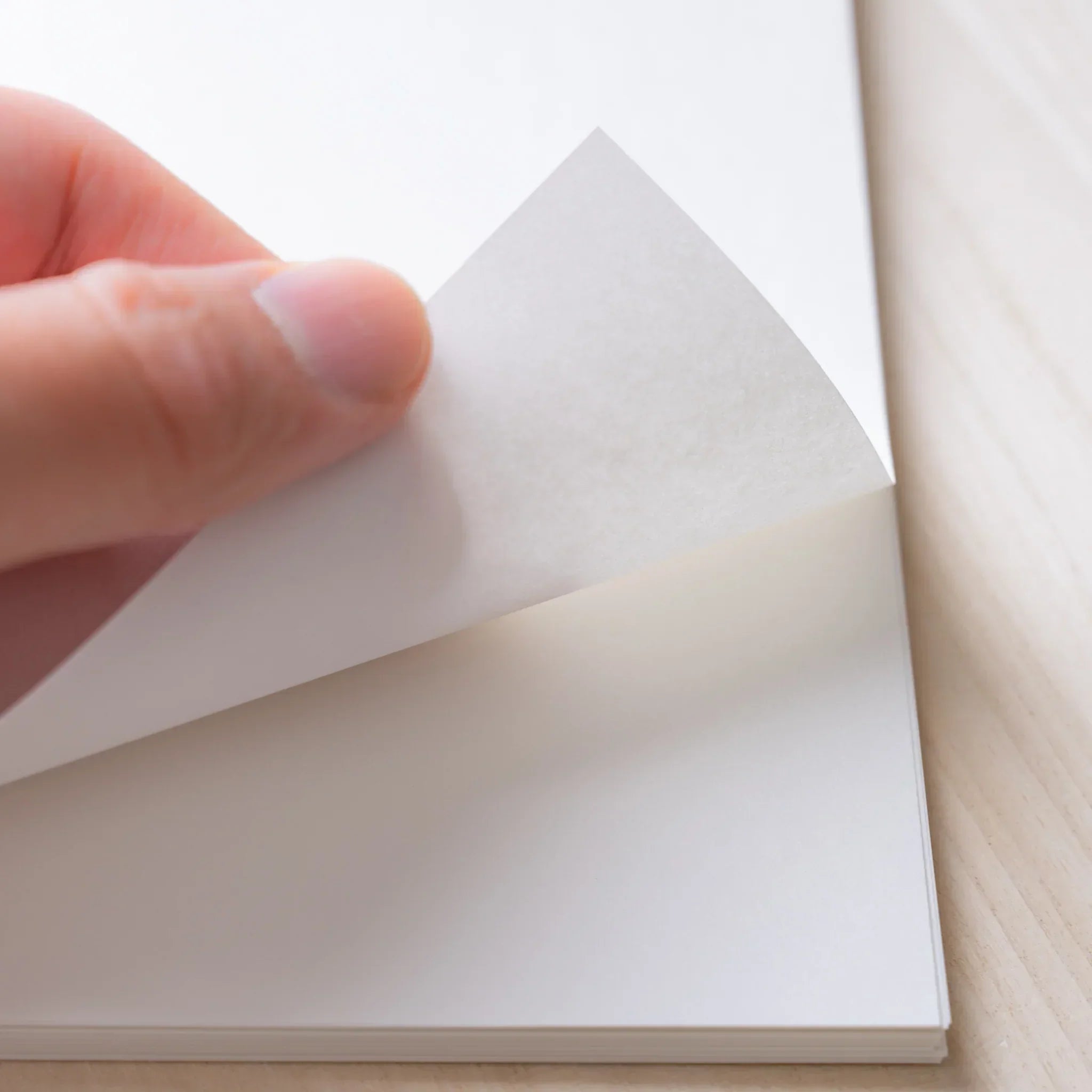 Hand peeling a top sheet from a Yamamoto Paper Meringue A4 loose leaf paper stack.