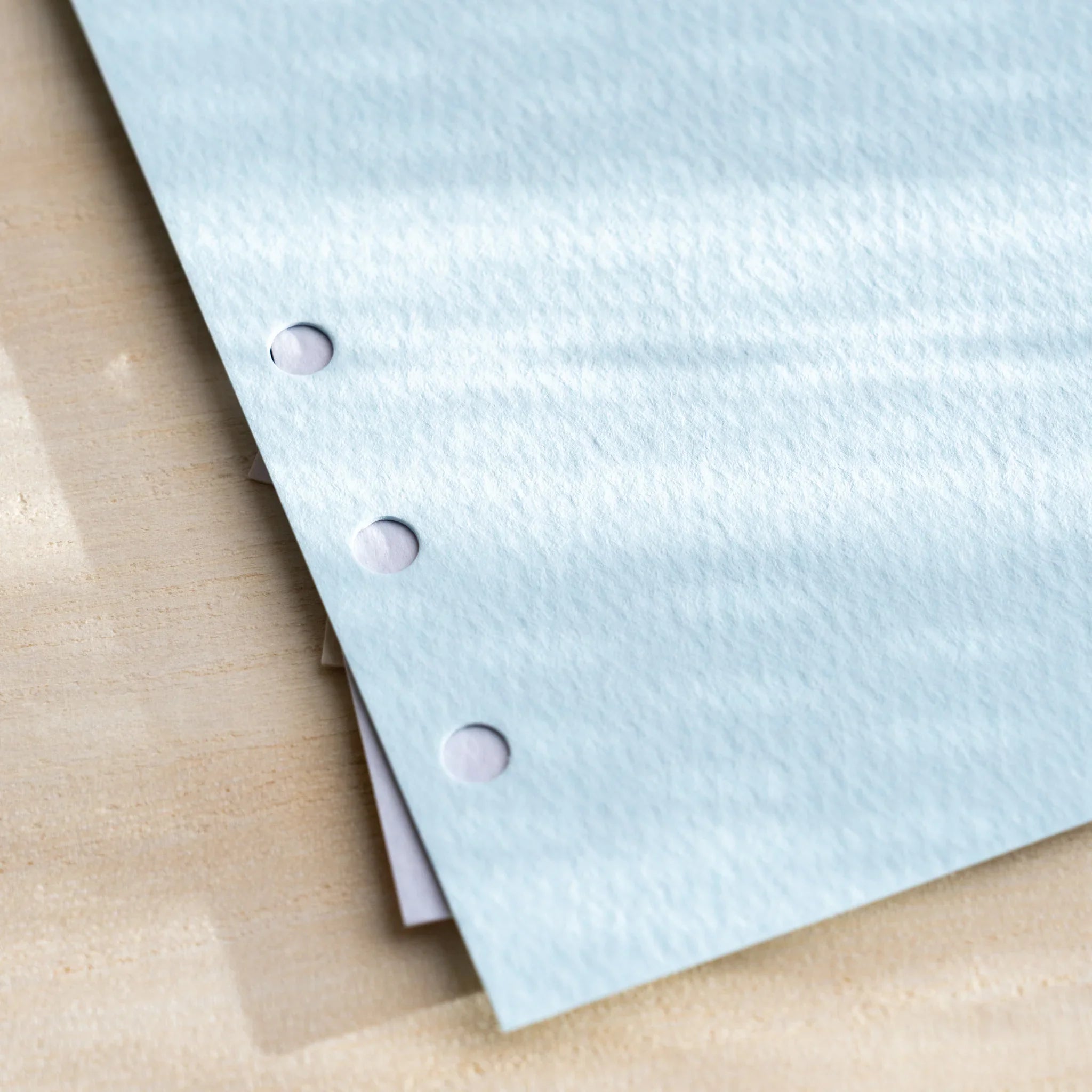 Japanese Stationery Mermaid top-tab index divider for Bible size planners close-up of pastel blue sheet with punched holes.