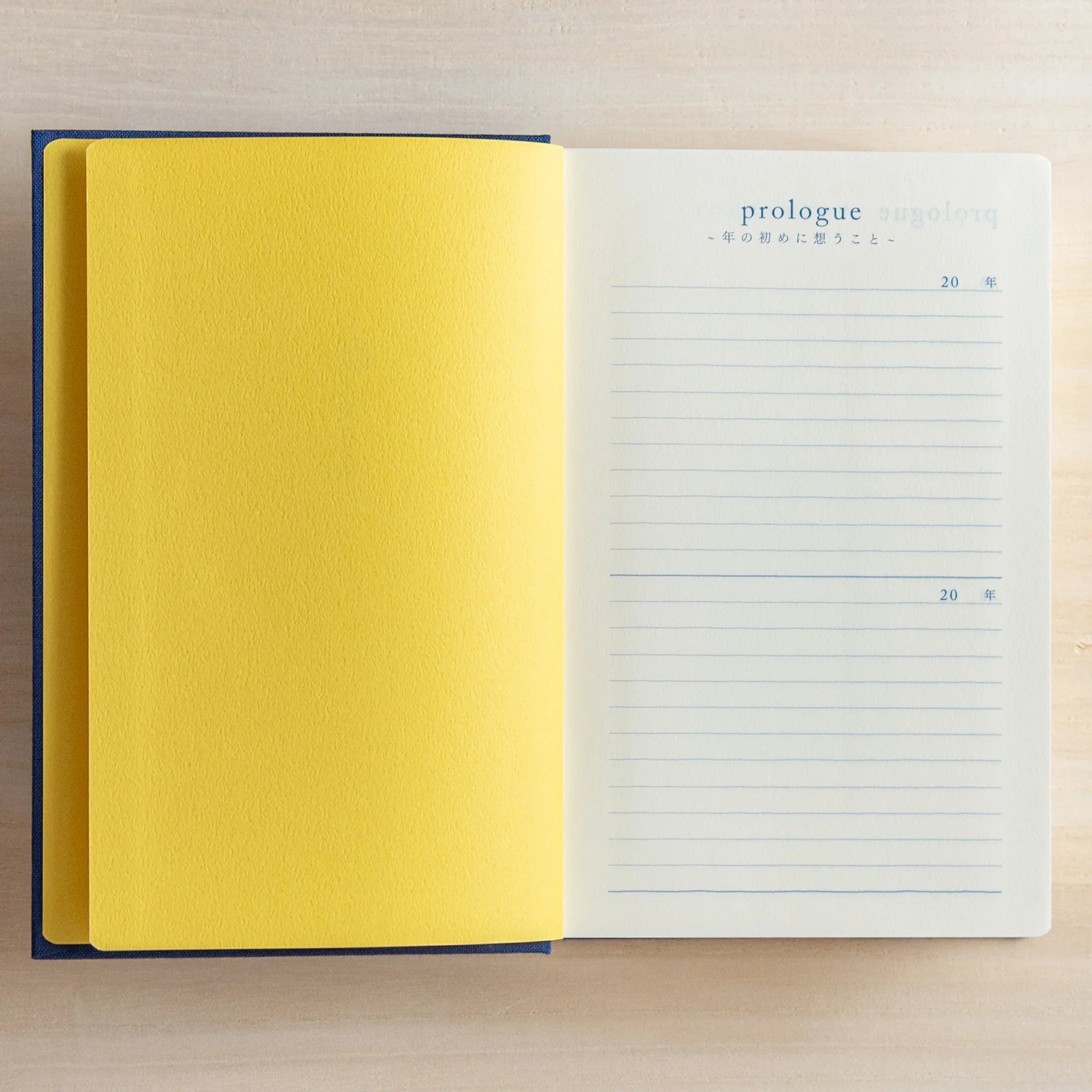 Open Midori Japanese journal 10-year diary gate design showing yellow cover page and prologue lined page with year headings.