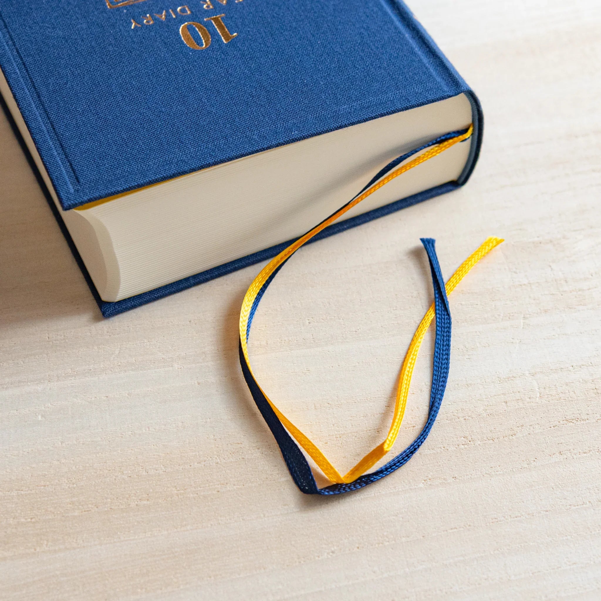 Midori Japanese journal 10-year diary gate design in navy with yellow and blue ribbon bookmarks.