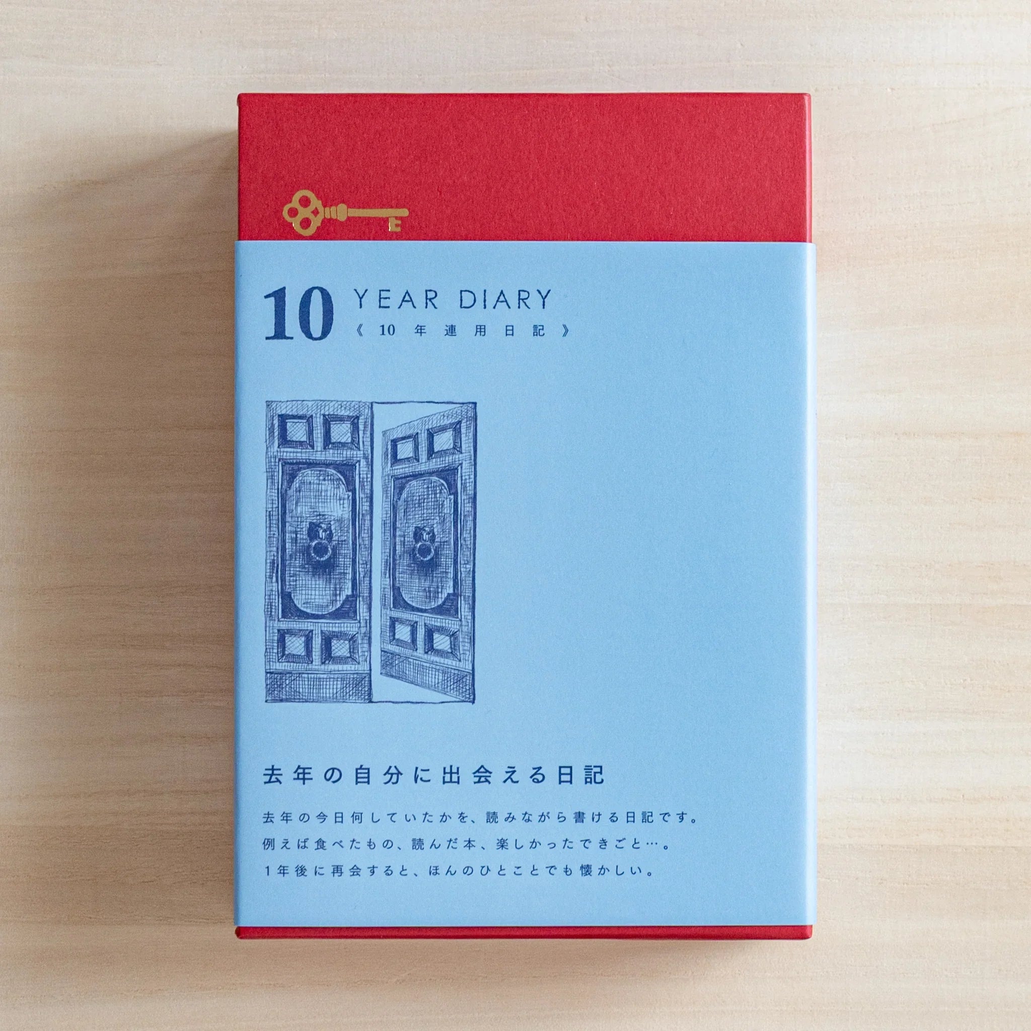 Front view of Midori Japanese journal 10-year diary gate design with red top and blue box and door illustration.