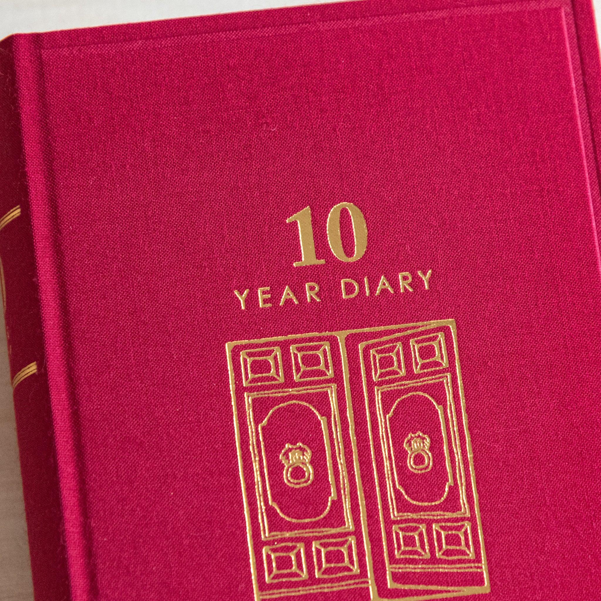 Close-up of Midori Japanese journal 10-year diary gate design red cover with golden text and door illustration.
