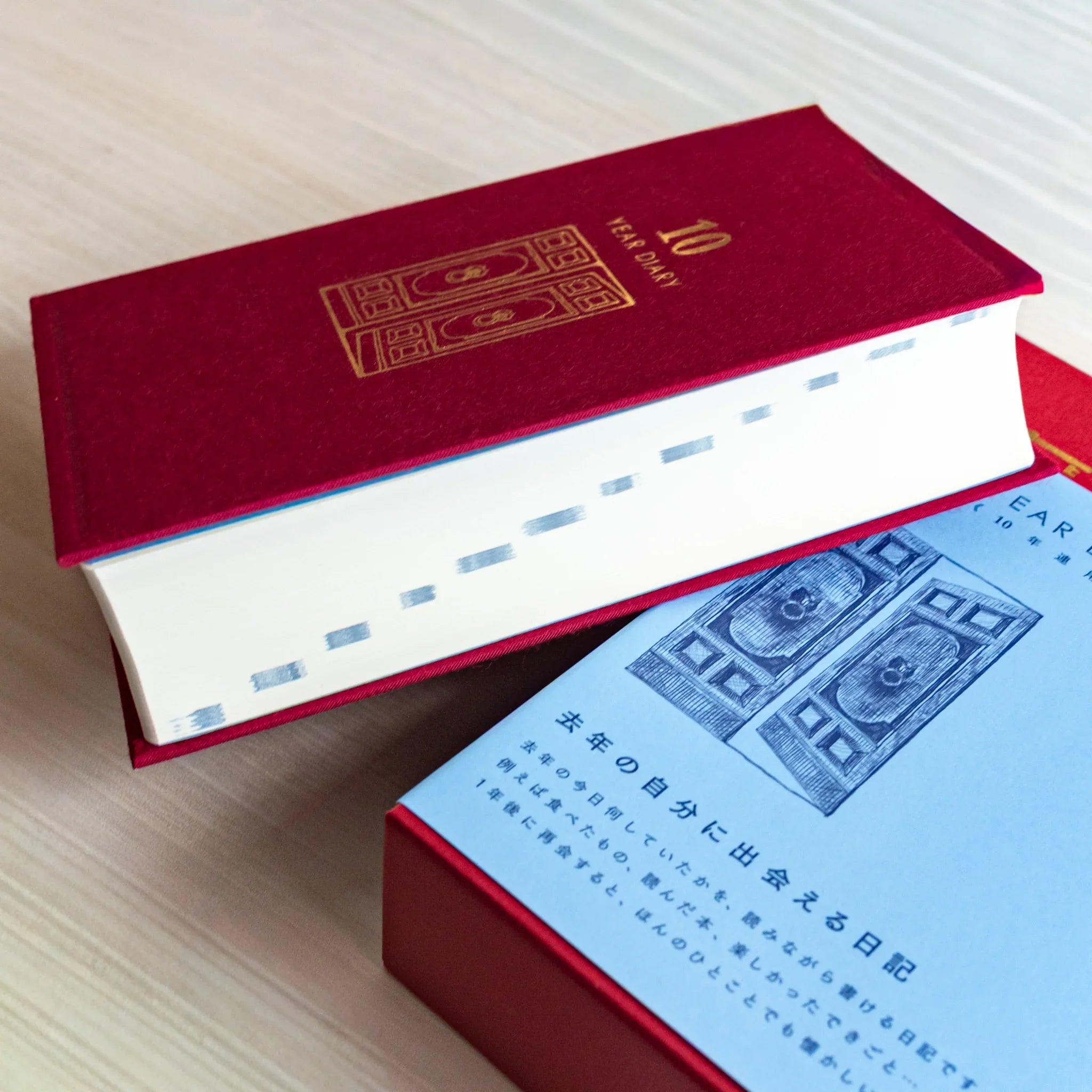 Midori Japanese journal 10-year diary gate design red book resting on blue slipcase with door illustration.