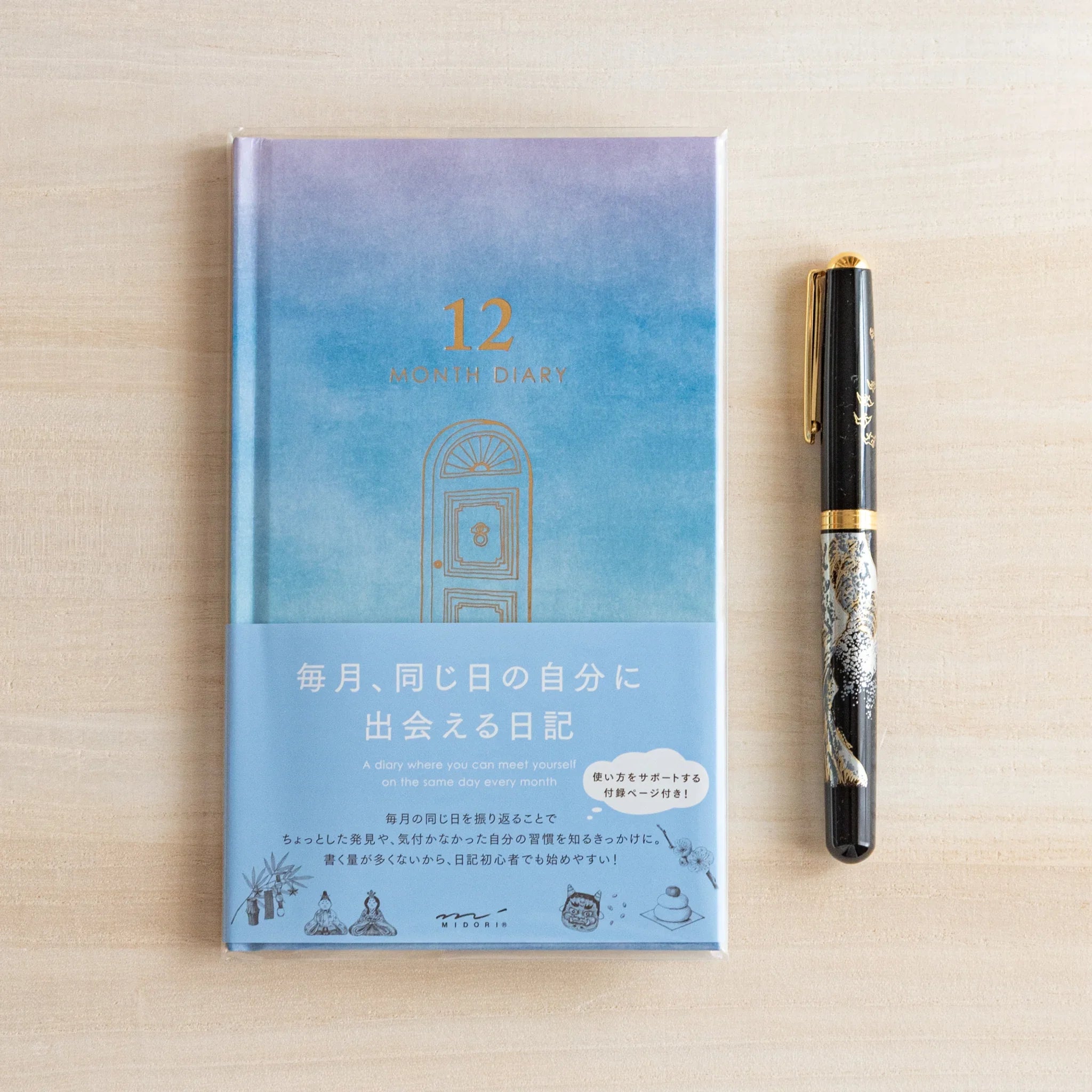 Midori Japanese journal with gate design and blue gradient cover, shown on desk beside an elegant pen.
