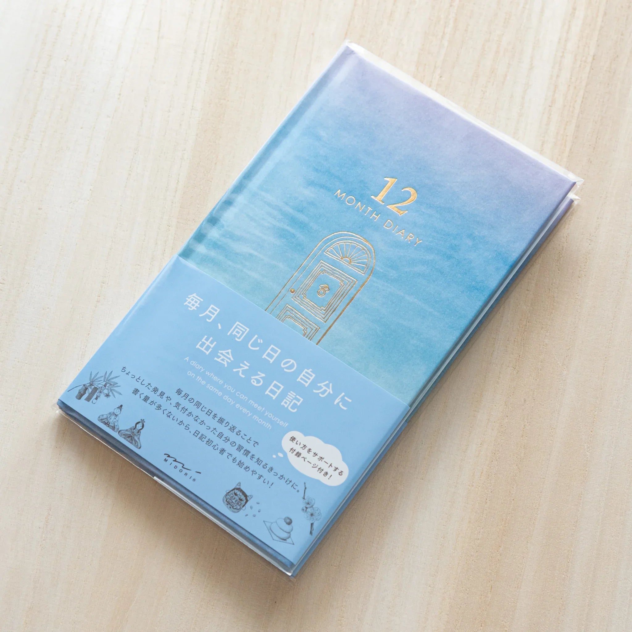 Angled view of Midori Japanese journal in gate design, blue gradient cover and paper wrap, on wood.