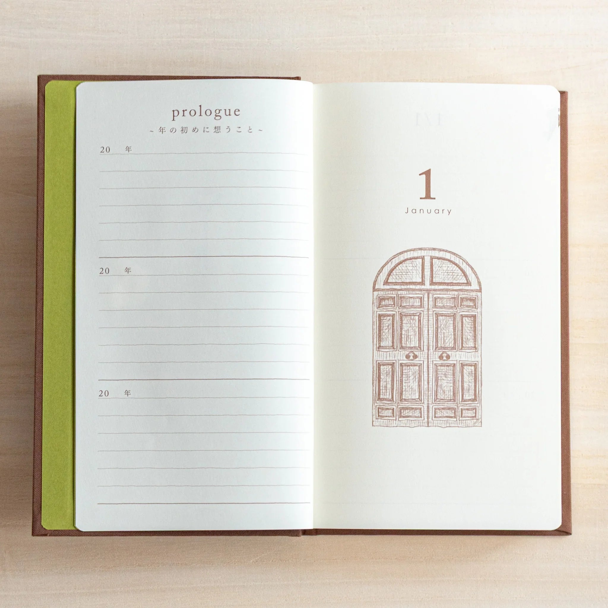 Open Midori Japanese Journal showing January 1 page with brown gate illustration and lined section on wooden desk.