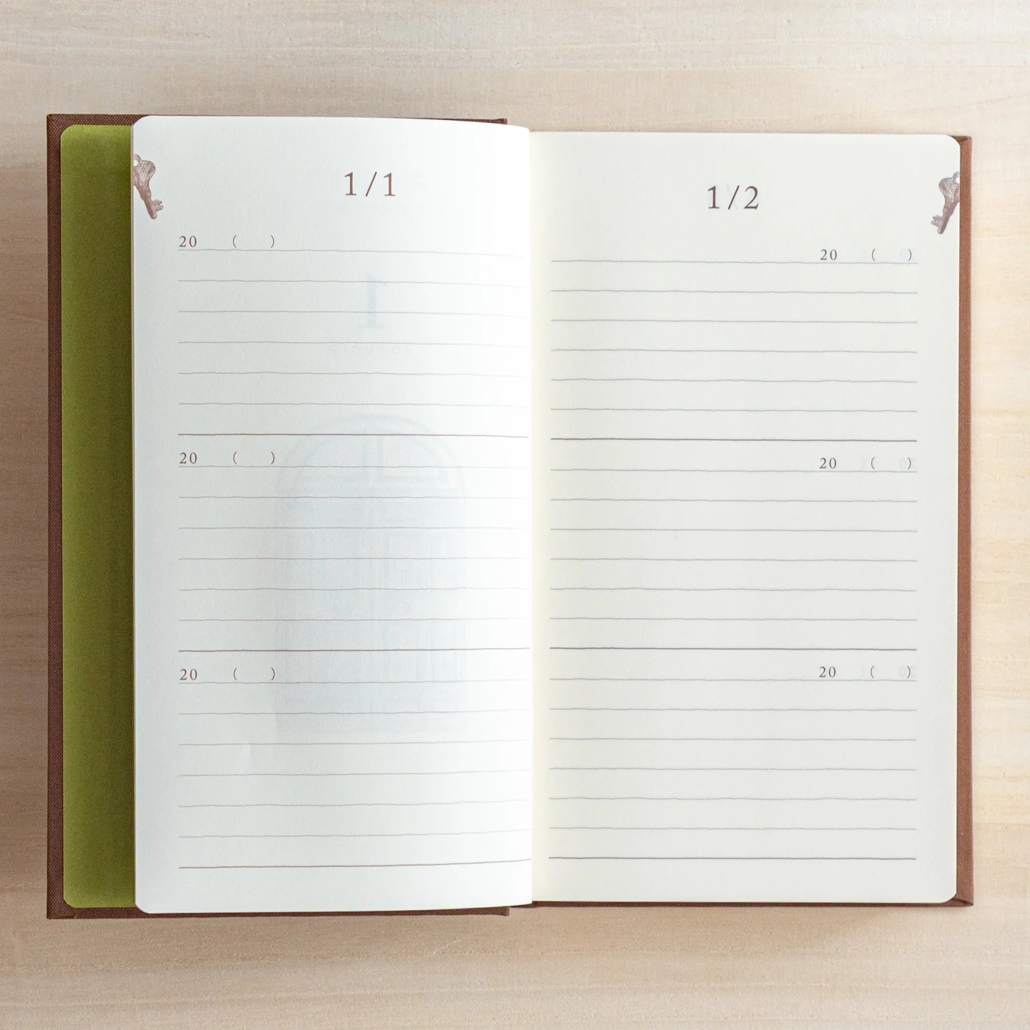 Open Midori Japanese Journal showing January 1 and January 2 pages with lined sections on a light wooden desk.