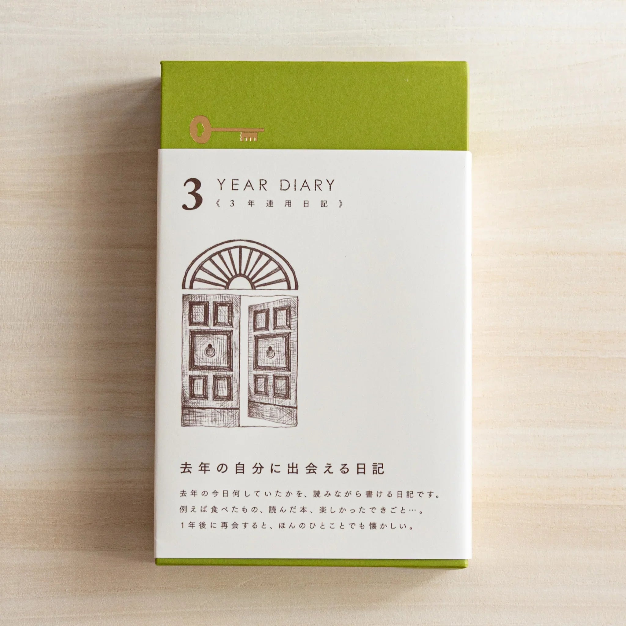 Front view of the Midori Japanese journal in its green slipcase, featuring a brown door illustratio packaging design.
