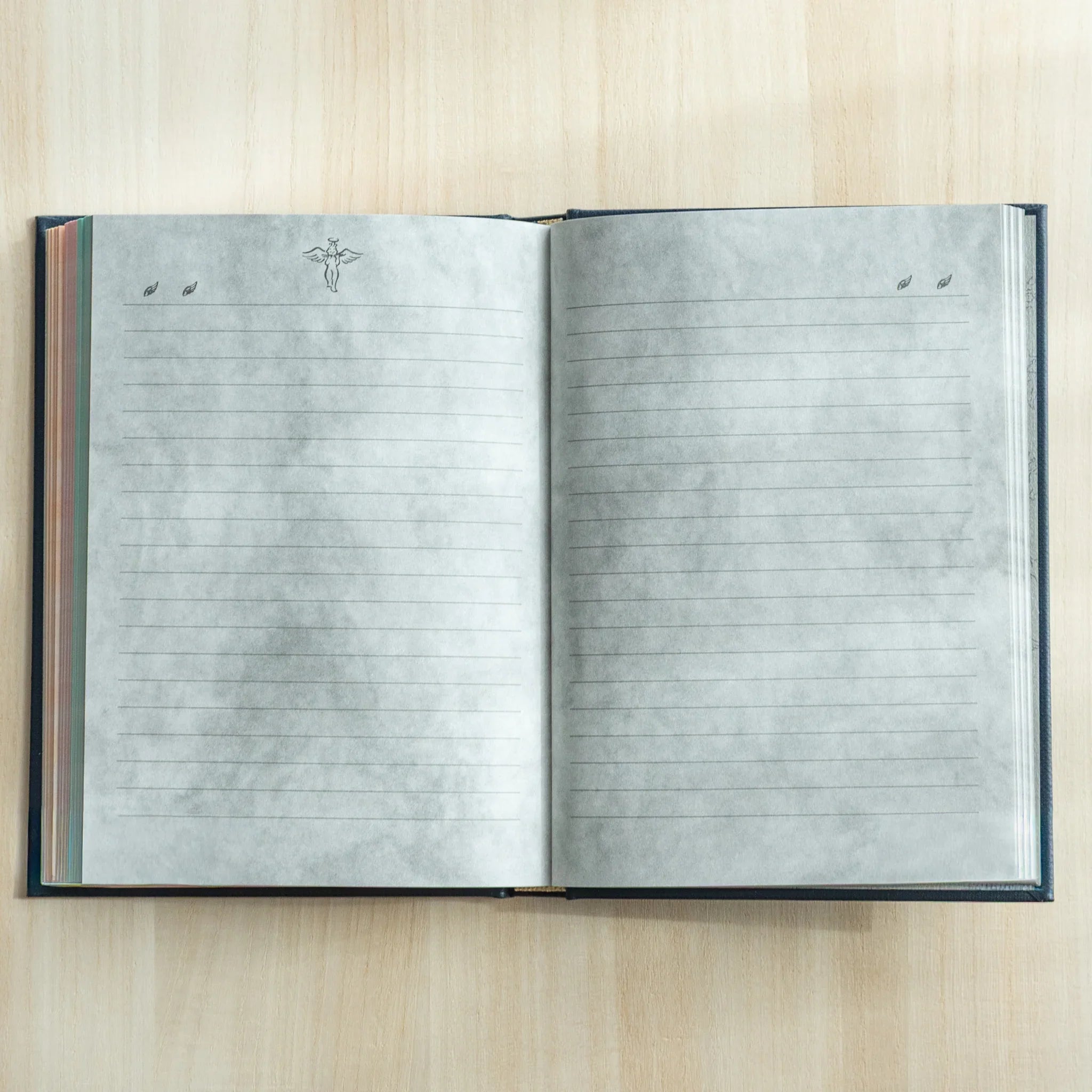 Open Midori Angel Motif Journal featuring two lined pages with grey watercolor wash and small angel and leaves illustrations