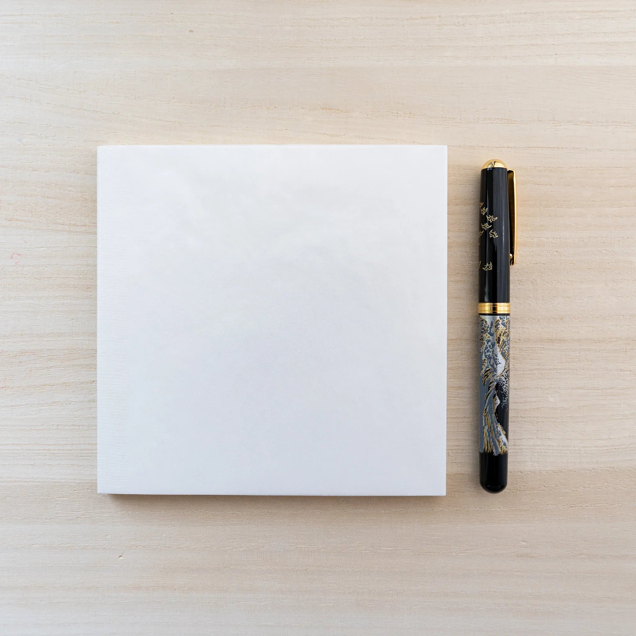 Square cream MD Cotton Notebook A5 Square beside a marbled fountain pen on a wood surface