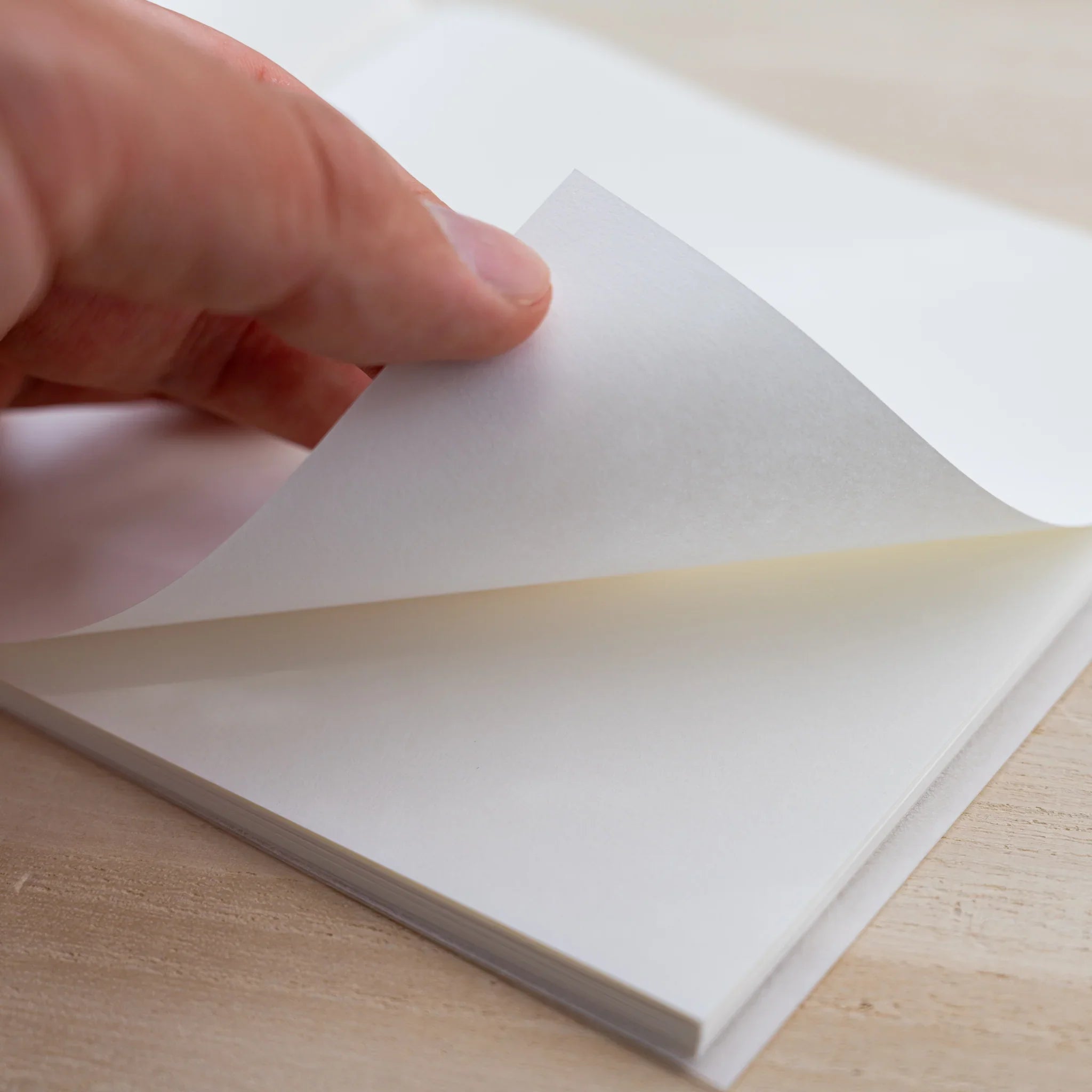 Hand turning a blank cream page of the MD Cotton Notebook A5 Square