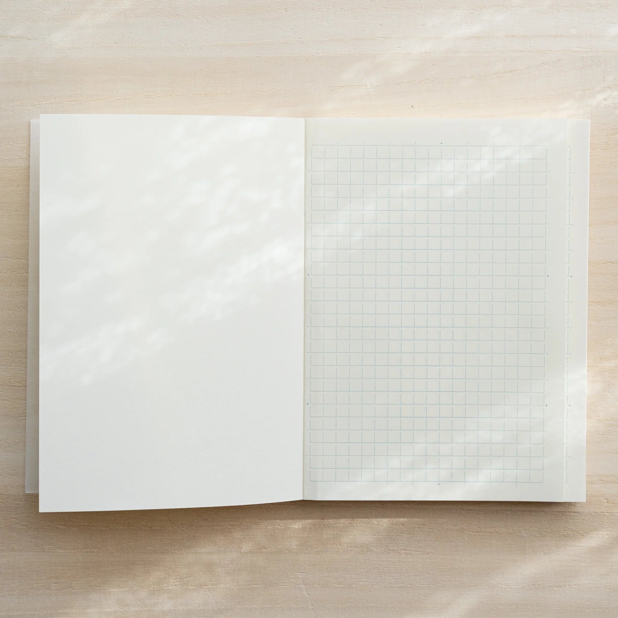 Midori MD Notebook A6 Grid open flat, blank white left page and ivory grid page on right, center spine visible
