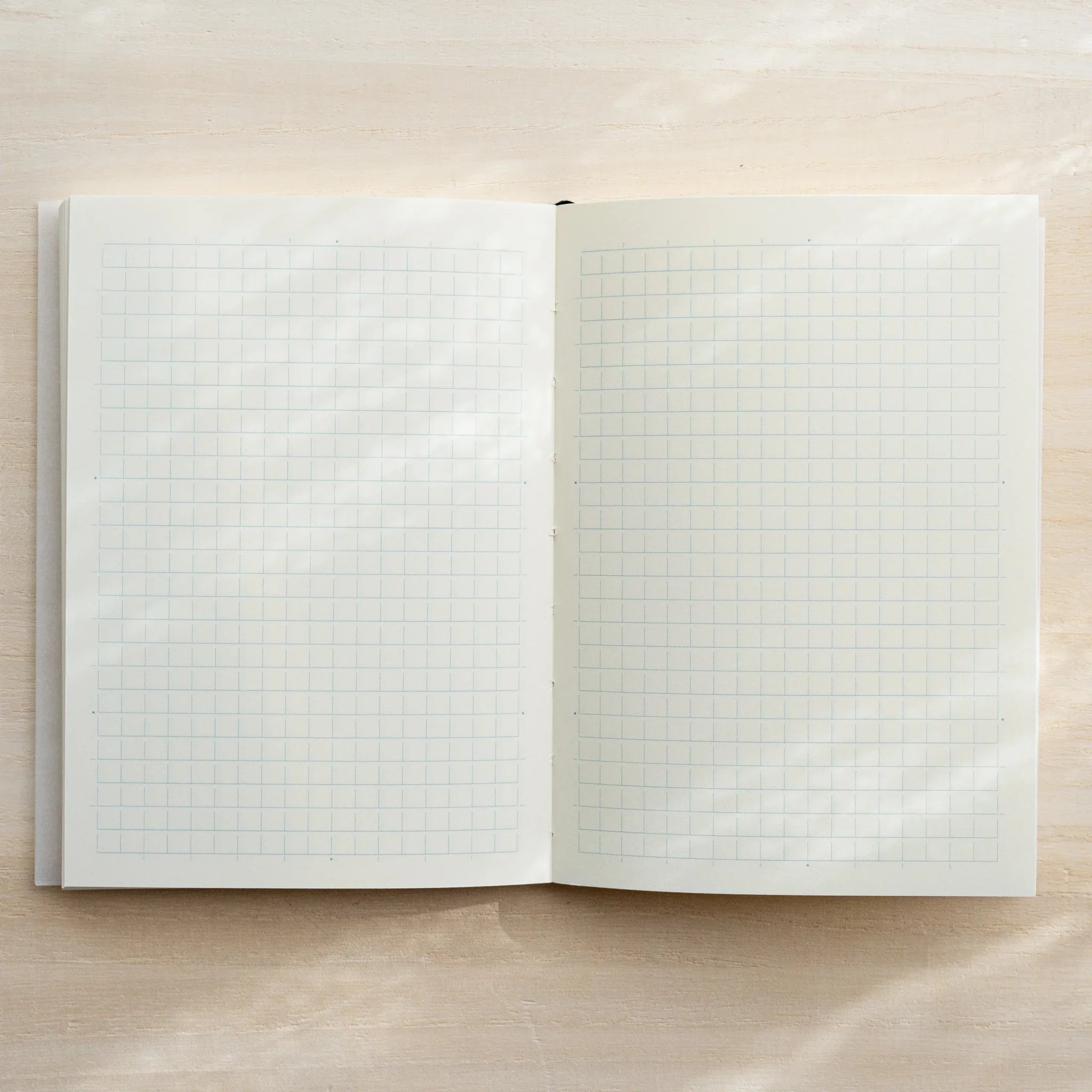 Midori MD Notebook A6 Grid open to ivory grid page spread, light gray grid lines visible, center spine visible