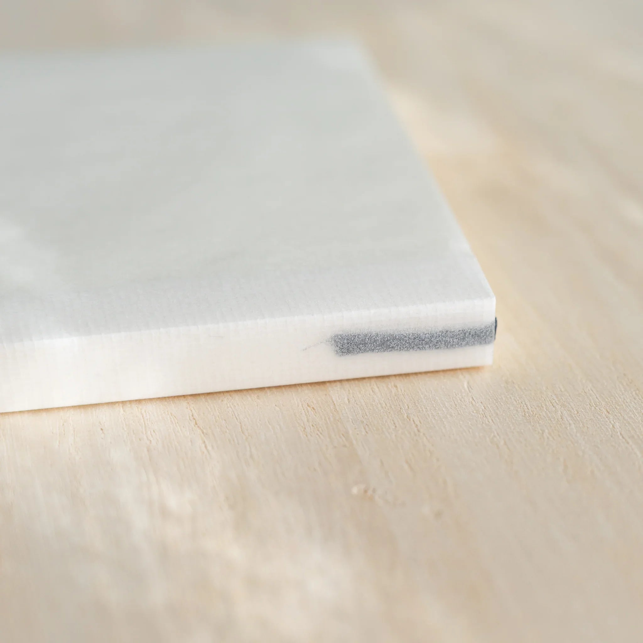 Midori MD Notebook A6 Grid corner view, white glassine cover with dark blue bookmark ribbon visible at bottom edge