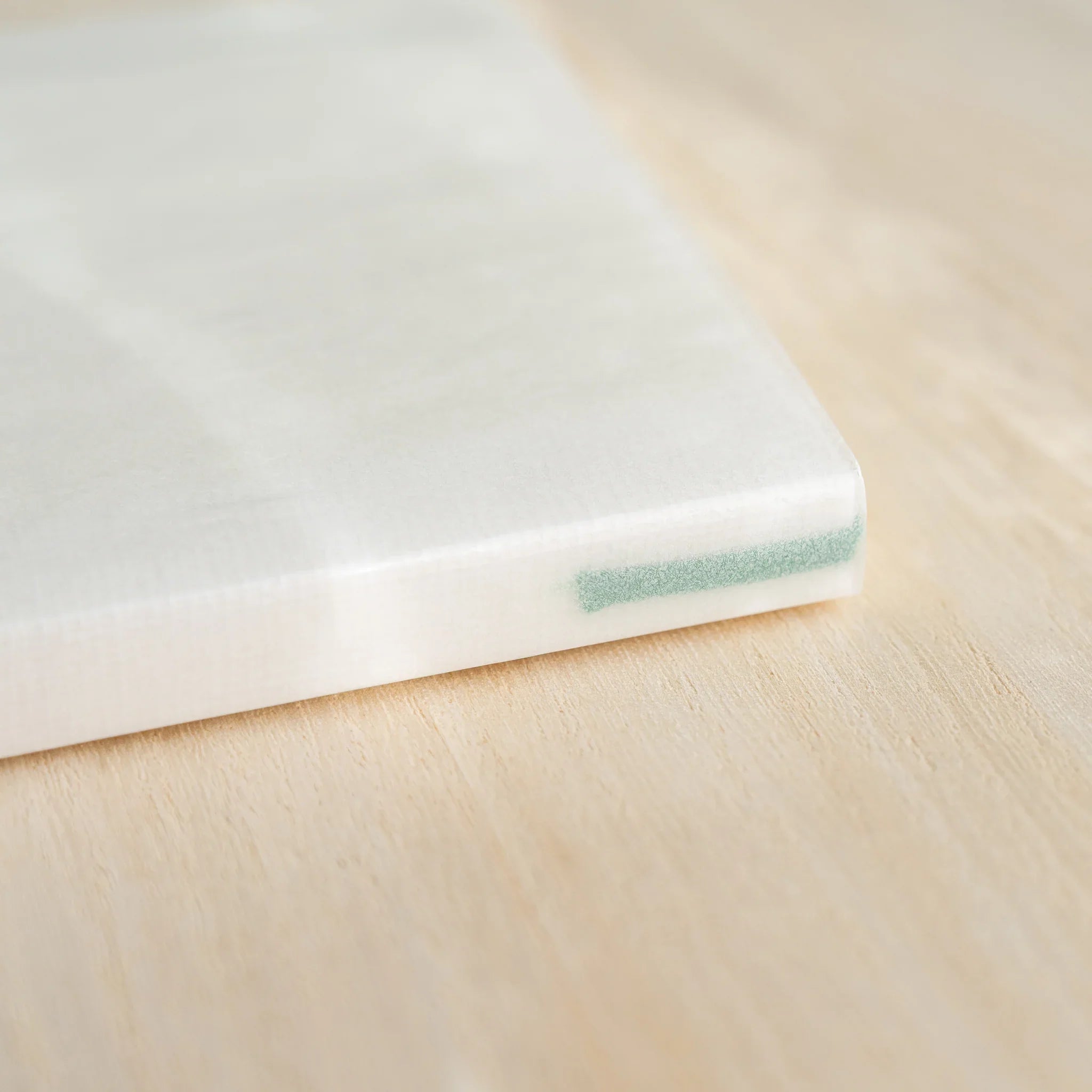 Midori MD Notebook A6 Lined corner close-up, white glassine cover with green bookmark ribbon visible at bottom edge