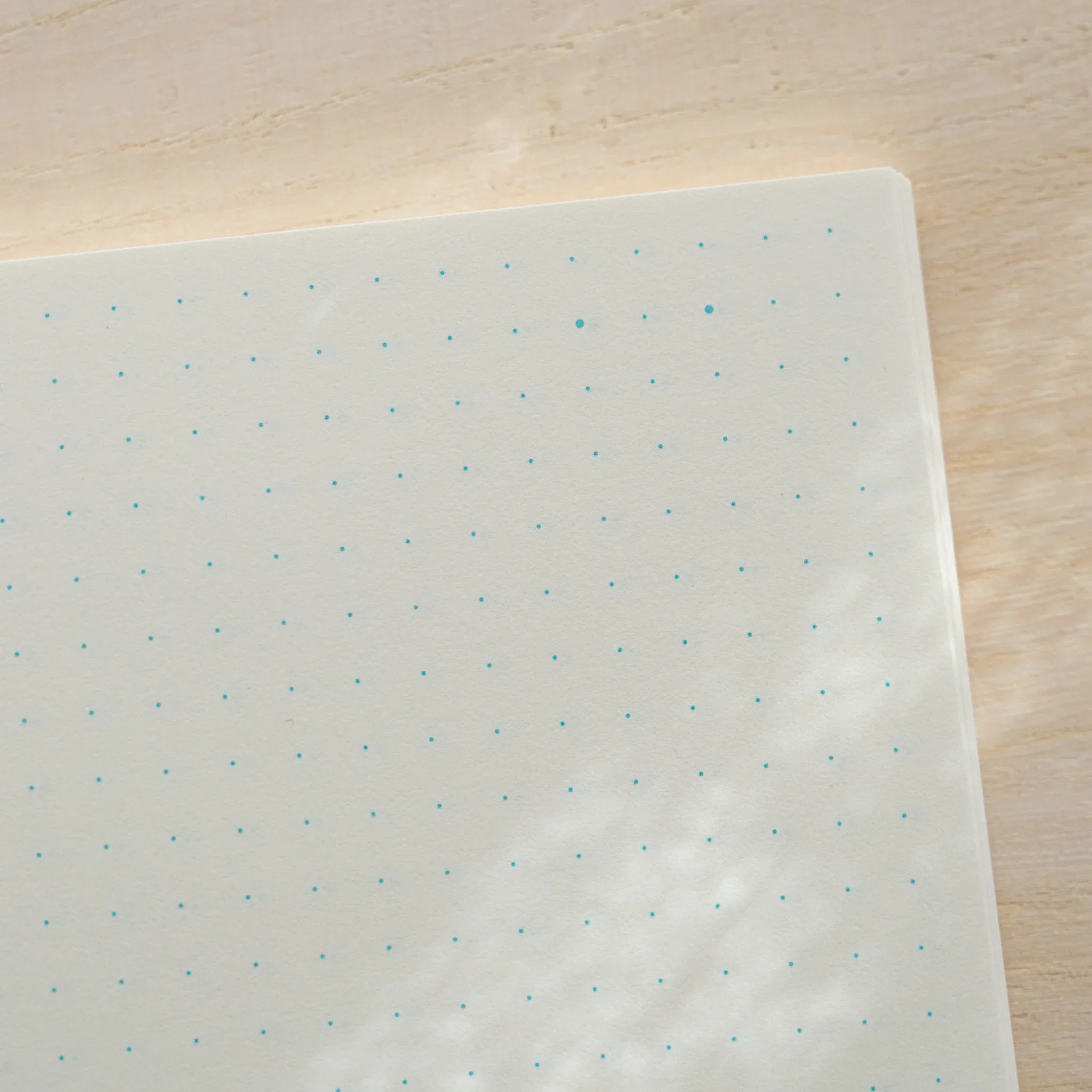 Close-up of Midori MD Notebook A6 dot grid page, ivory paper with evenly spaced teal dots, page corner visible