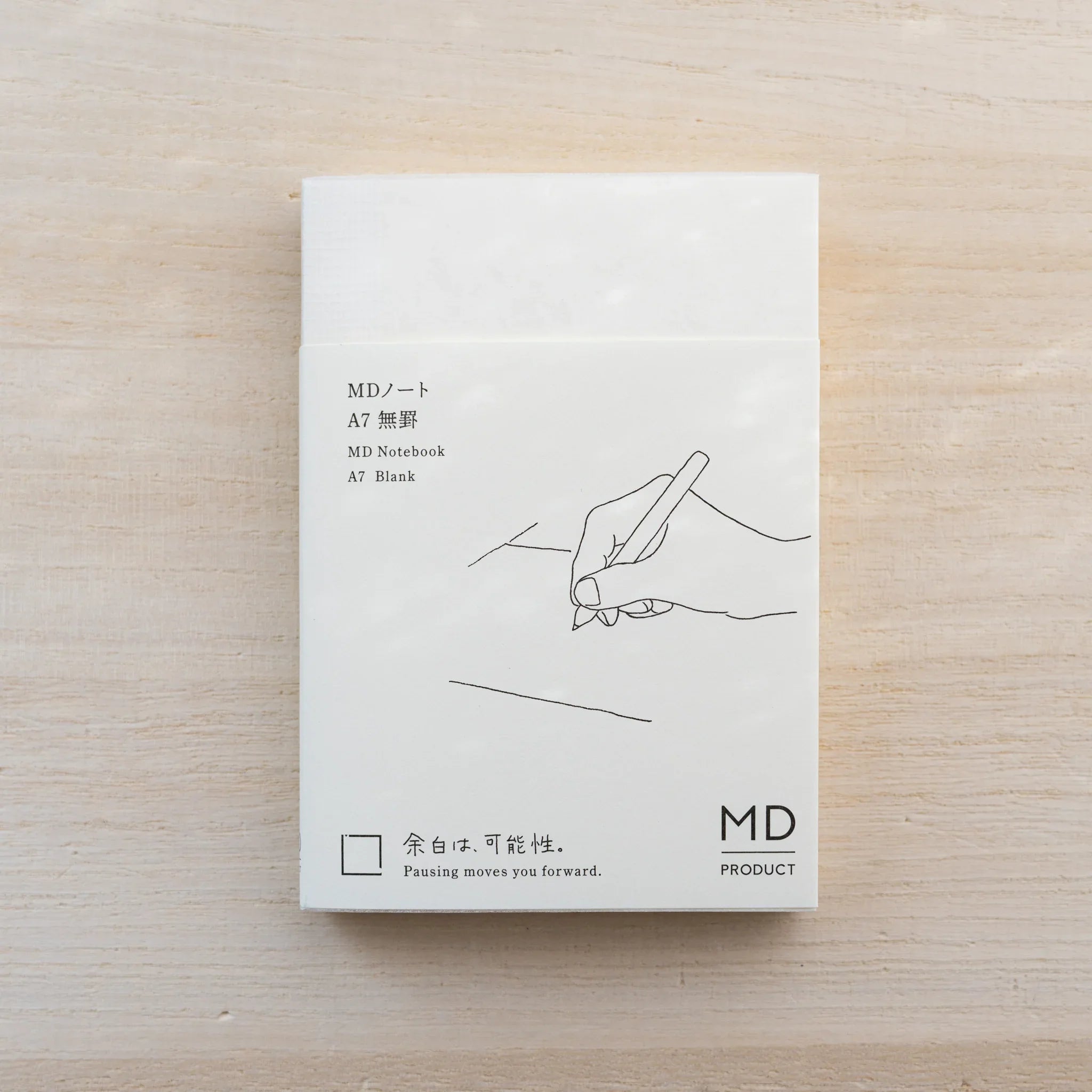 MD Notebook A7 Blank in cream cover with paper belly band and hand-with-pen line drawing