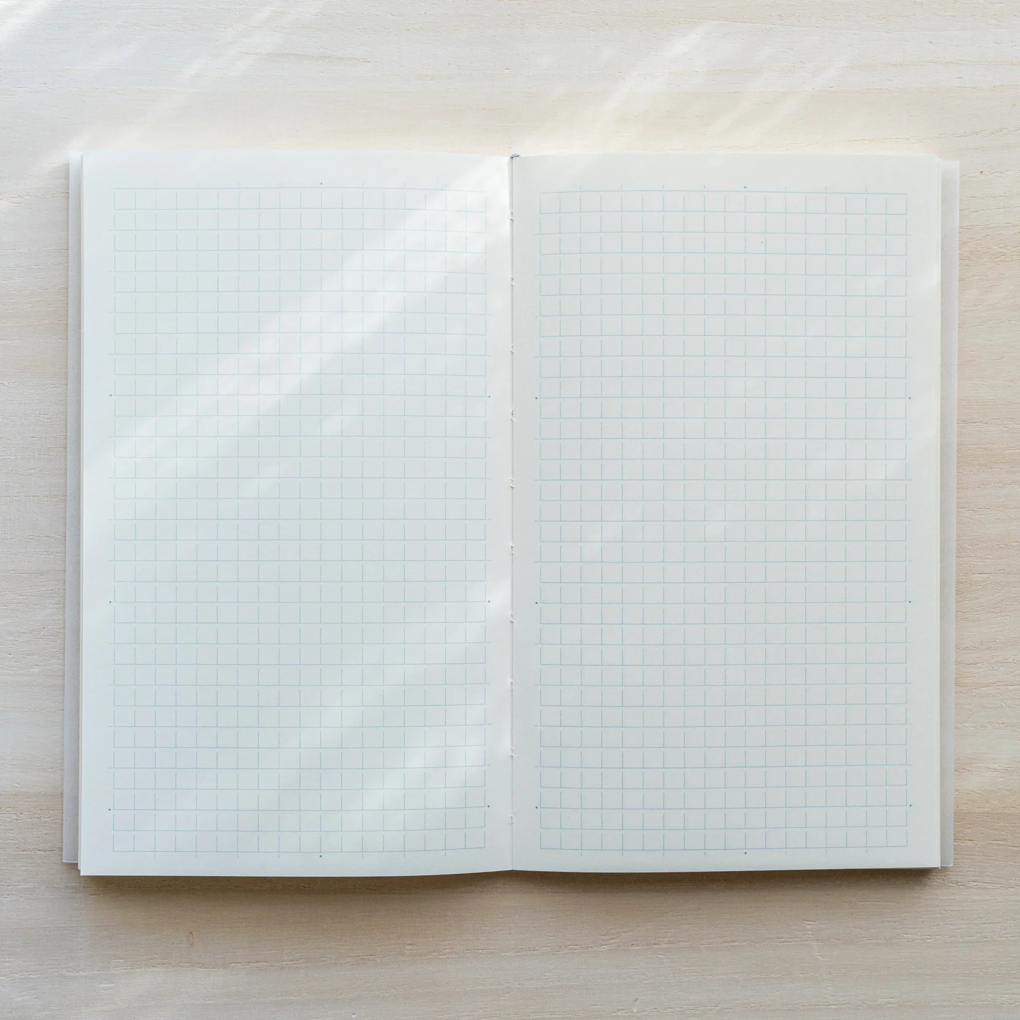 Midori MD Notebook B6 Slim Grid open flat, white grid spread on both pages, center spine visible, white paper