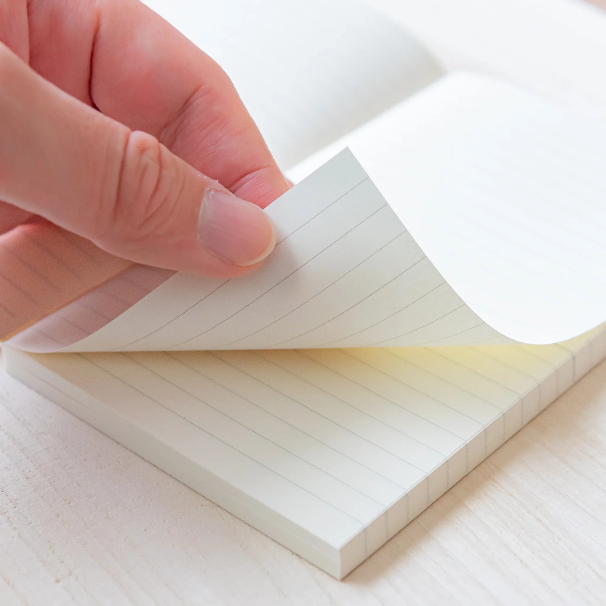 Japanese Notebook close-up of a hand flipping lined pages in a Midori MD B6 notebook, showing smooth cream paper.