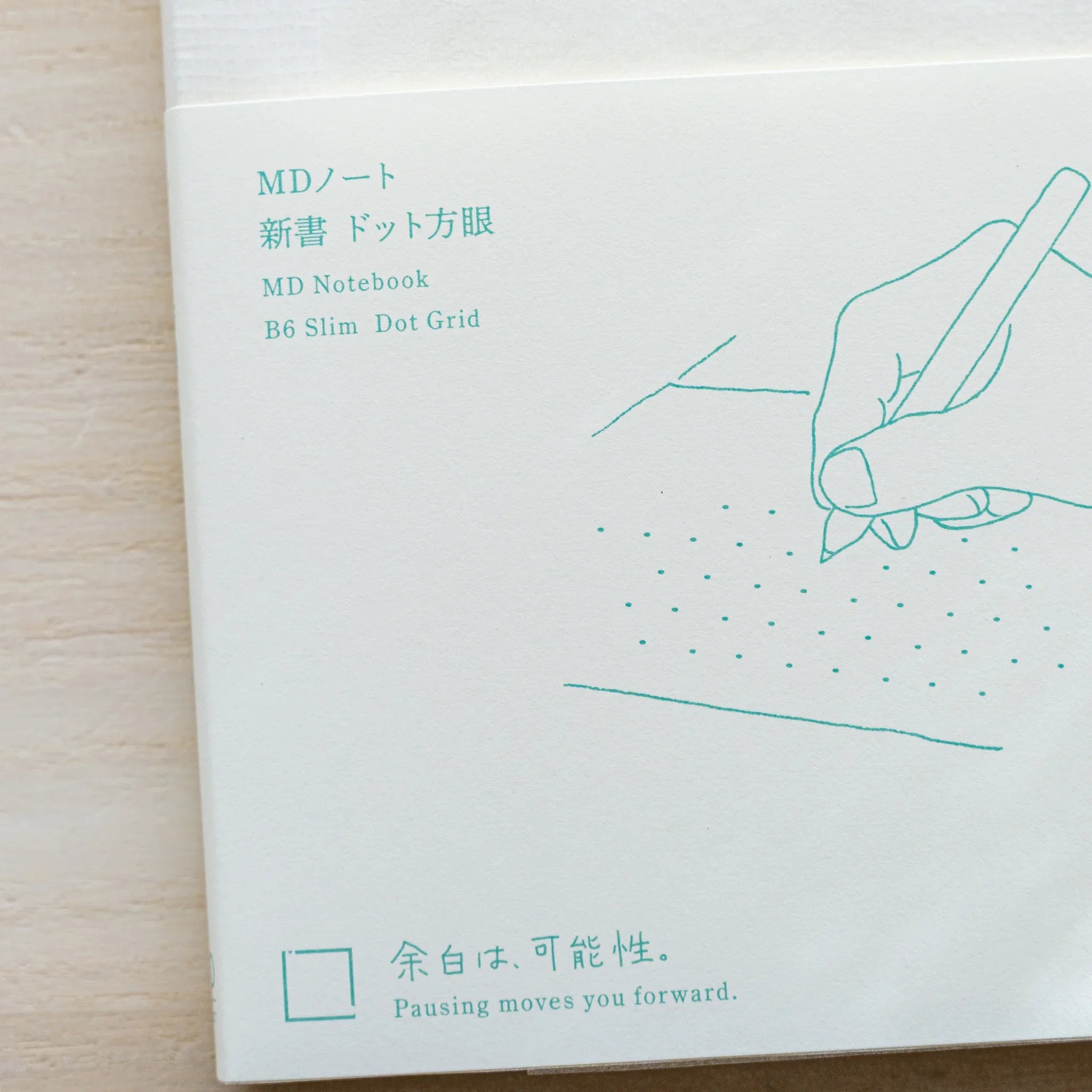 Midori MD Notebook B6 Slim Dot Grid cover close-up showing teal hand illustration with Japanese and English taglines