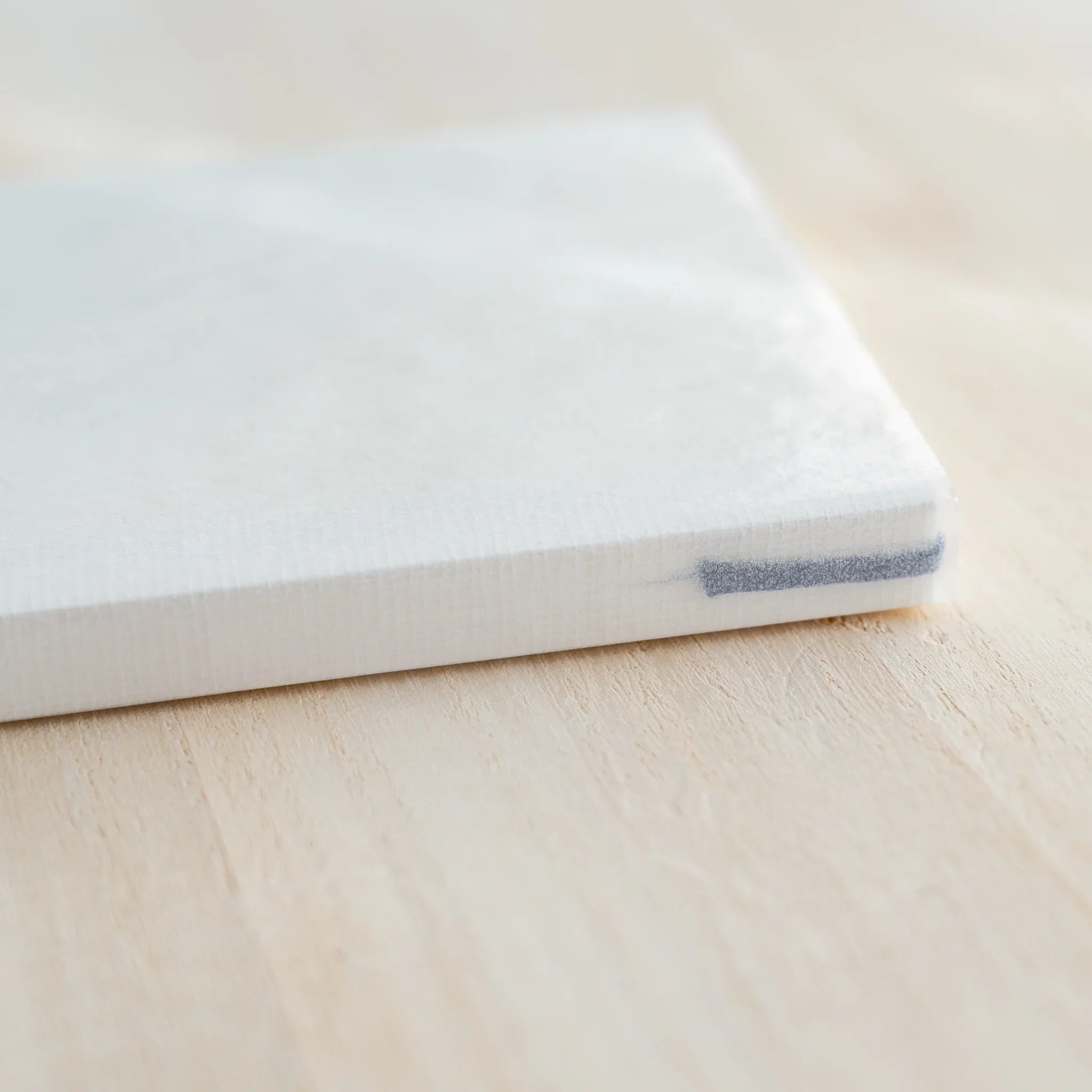 Close-up of Midori MD Notebook B6 Slim corner, white cover, ivory page edges, blue ribbon bookmark visible at spine