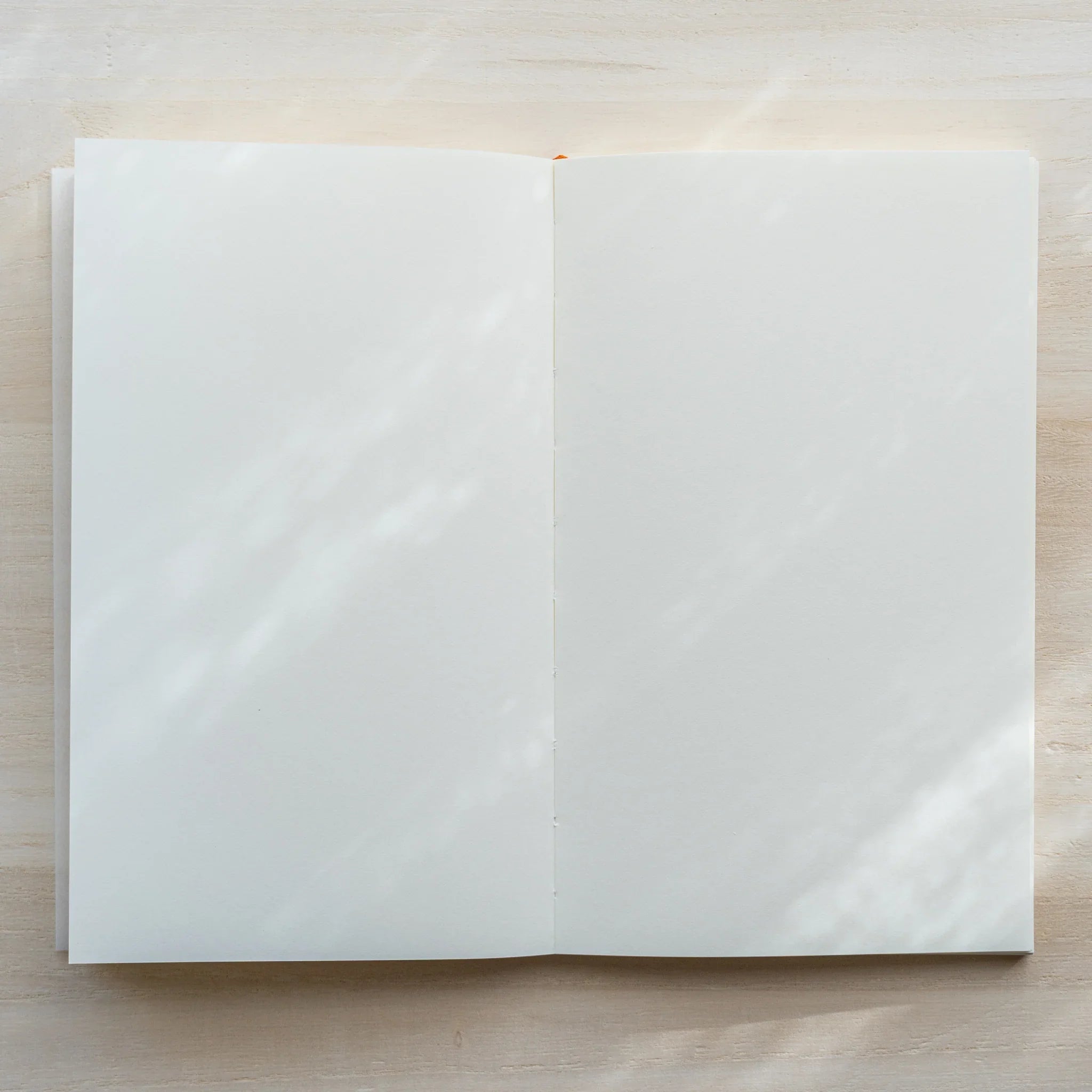 Midori MD Notebook B6 Slim Blank open flat showing completely blank white pages with orange bookmark ribbon, flat-lay
