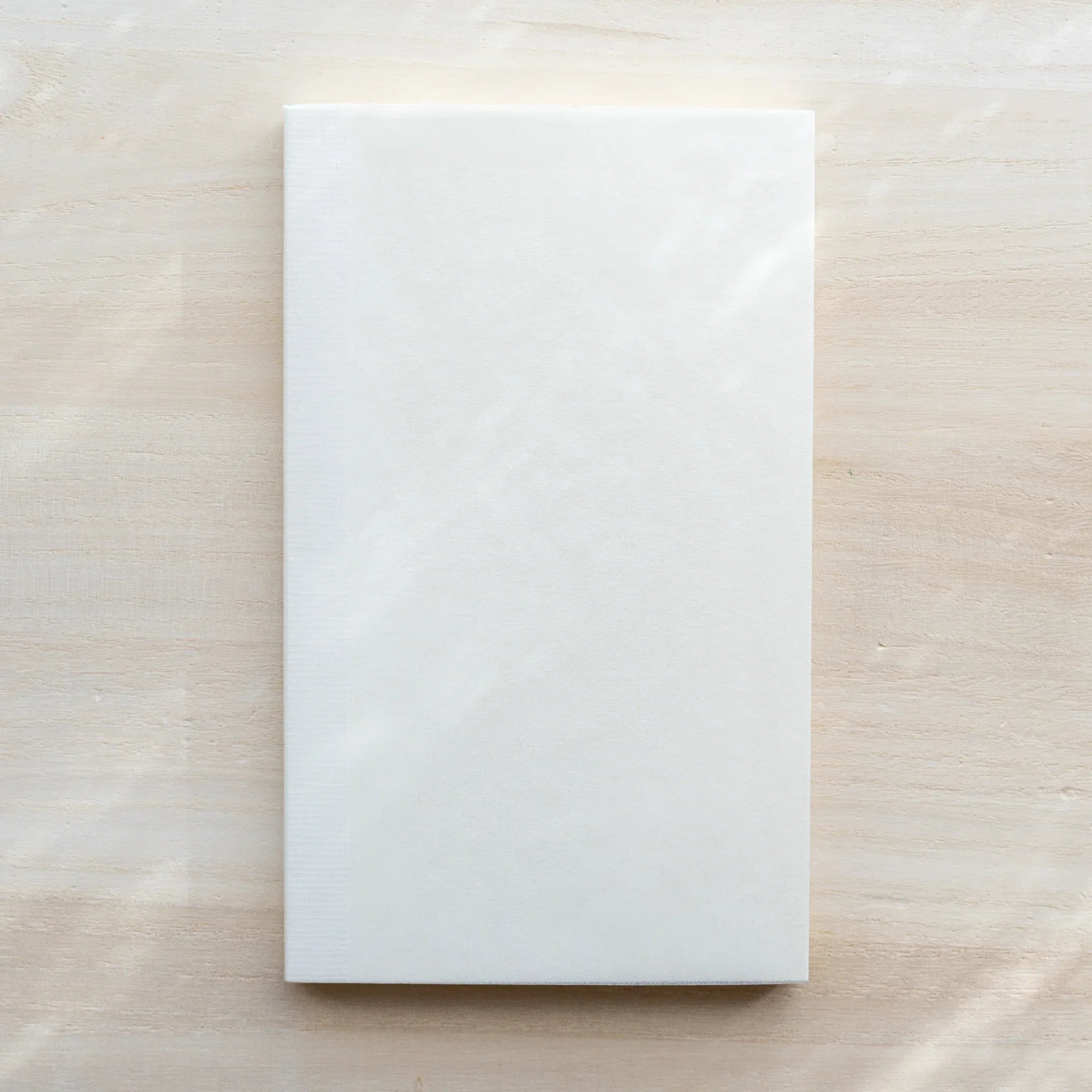 Midori MD Notebook B6 Slim plain white front cover on light wood surface, no text or design markings