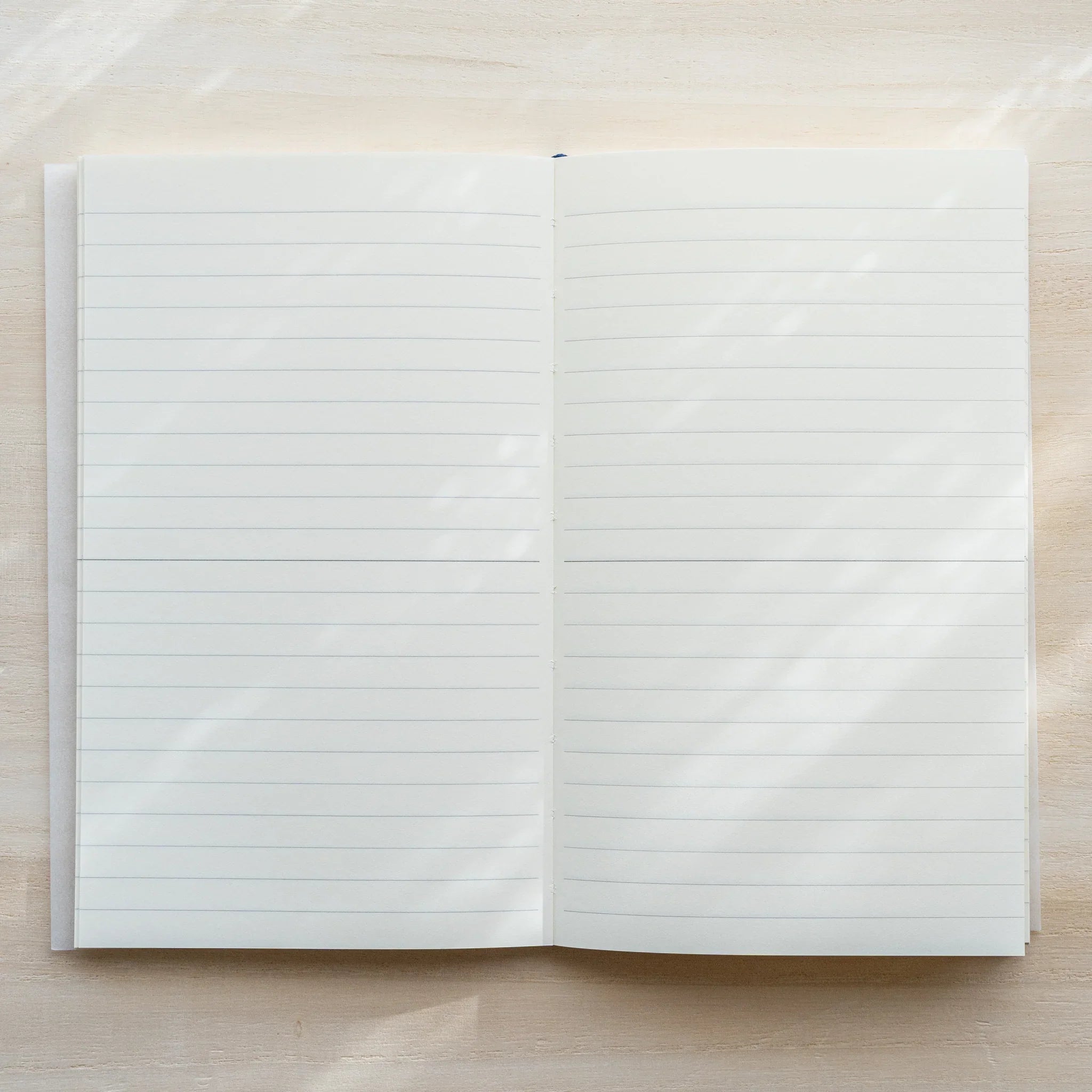 Midori MD Notebook B6 Slim Lined open flat, lined white pages spread, blue ribbon bookmark at top, center spine visible