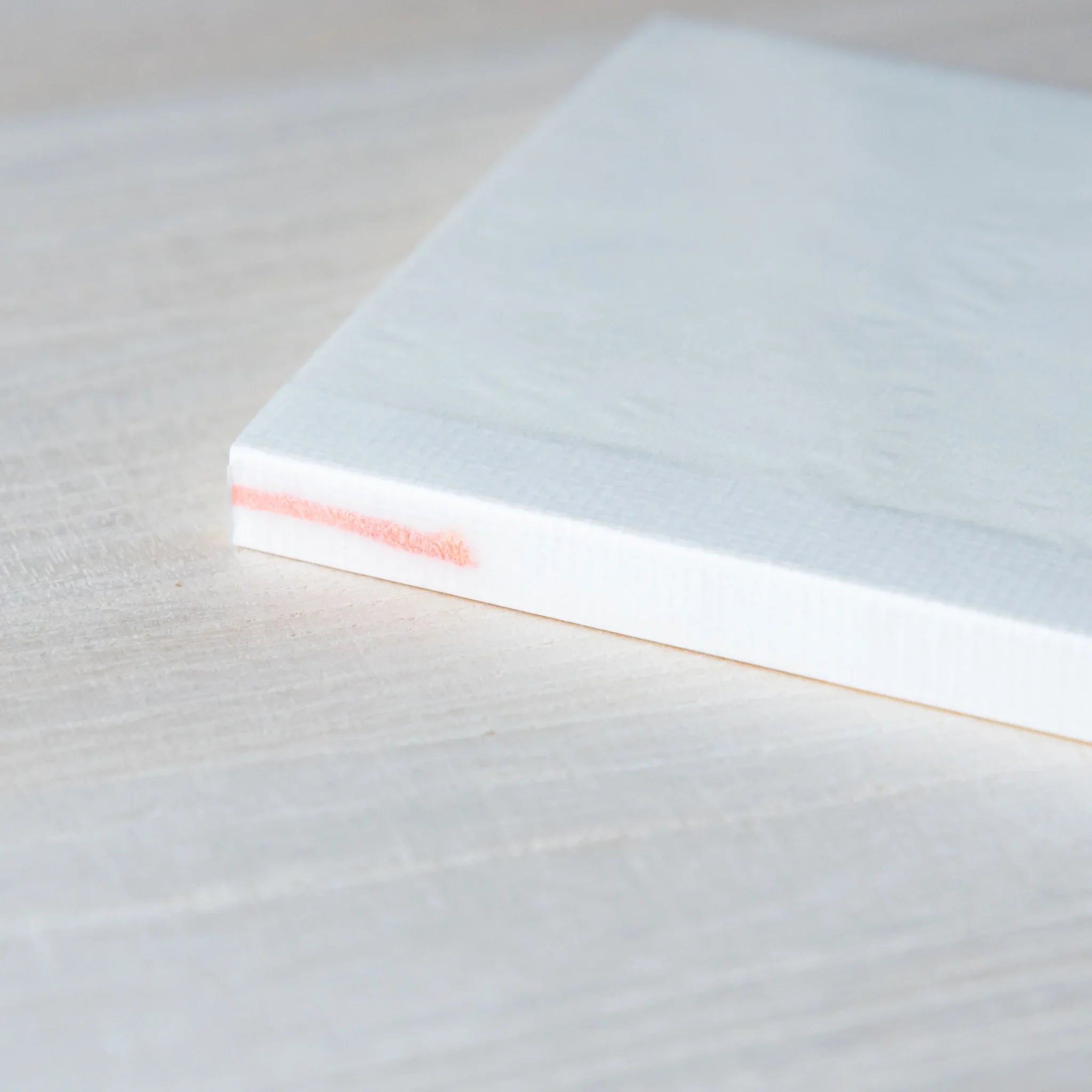 Japanese Notebook side view of a closed Midori MD B6 notebook, showing clean page edges and an orange ribbon bookmark peeking out.