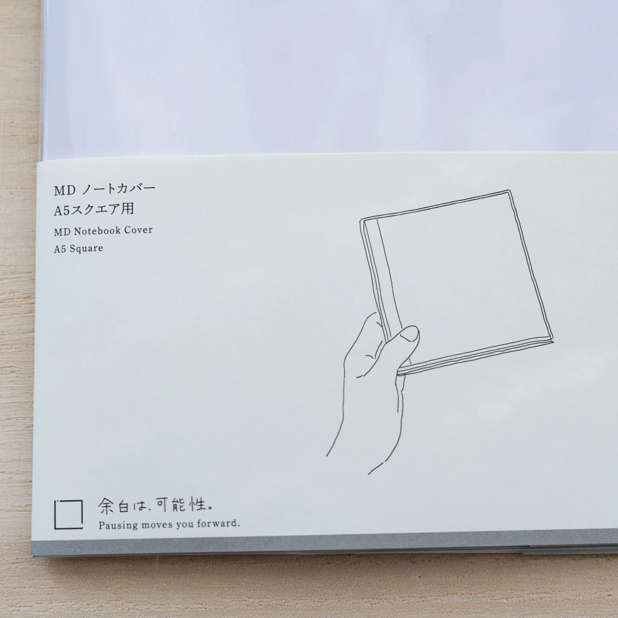 Insert card for Midori MD Notebook Cover A5 Square with line drawing of a hand holding a notebook
