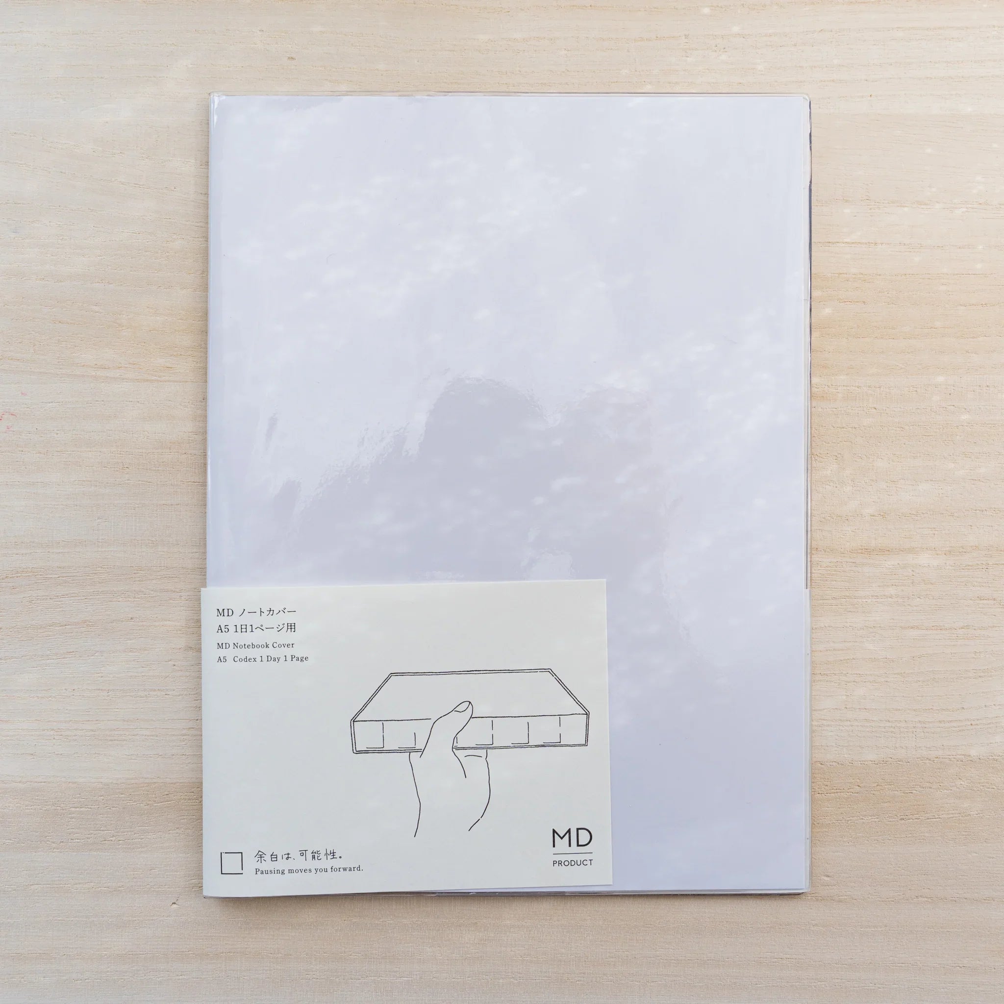 Midori MD Notebook Cover A5 Codex 1 Day 1 Page in packaging, clear PVC with insert card on wood