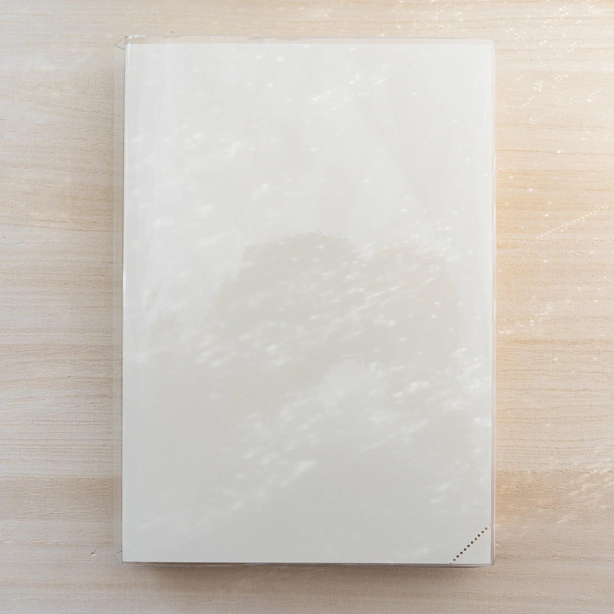 White MD notebook in clear PVC cover, closed front view with small corner perforation marks
