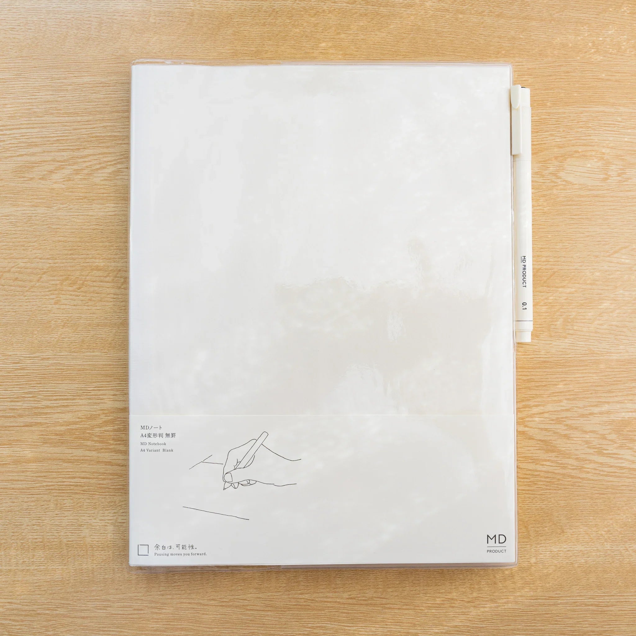 Clear PVC Midori MD Notebook Cover on a white notebook with a metal clip ruler tucked at the top edge