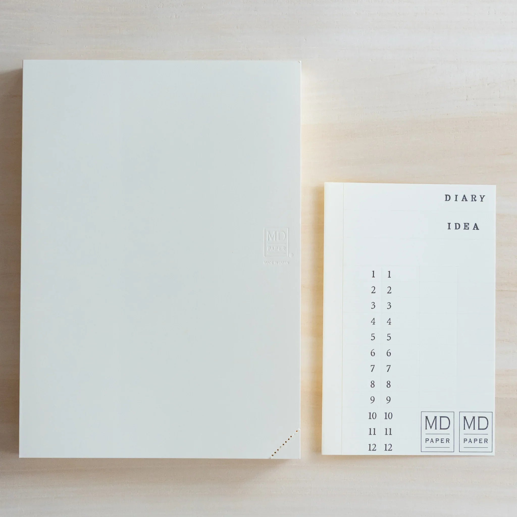 Top view of Midori Japanese journal with white cover next to numbered date index card labeled Diary Idea.