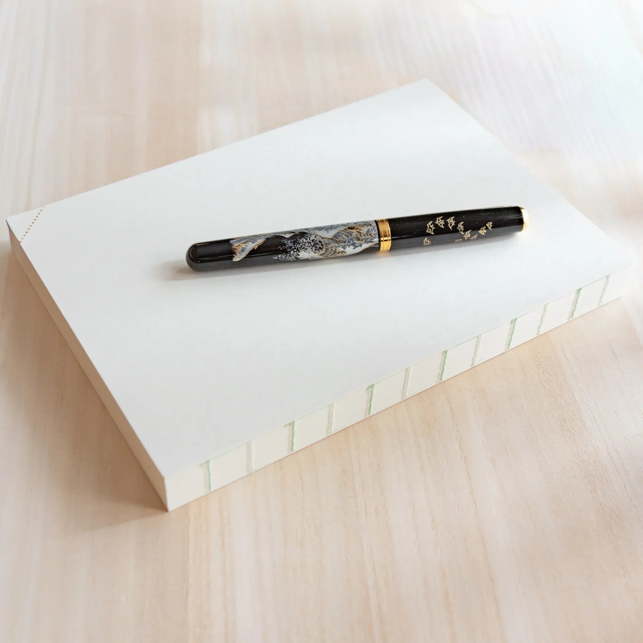 Top view of Midori Japanese journal with plain cream cover and marbled black and gold fountain pen on top.