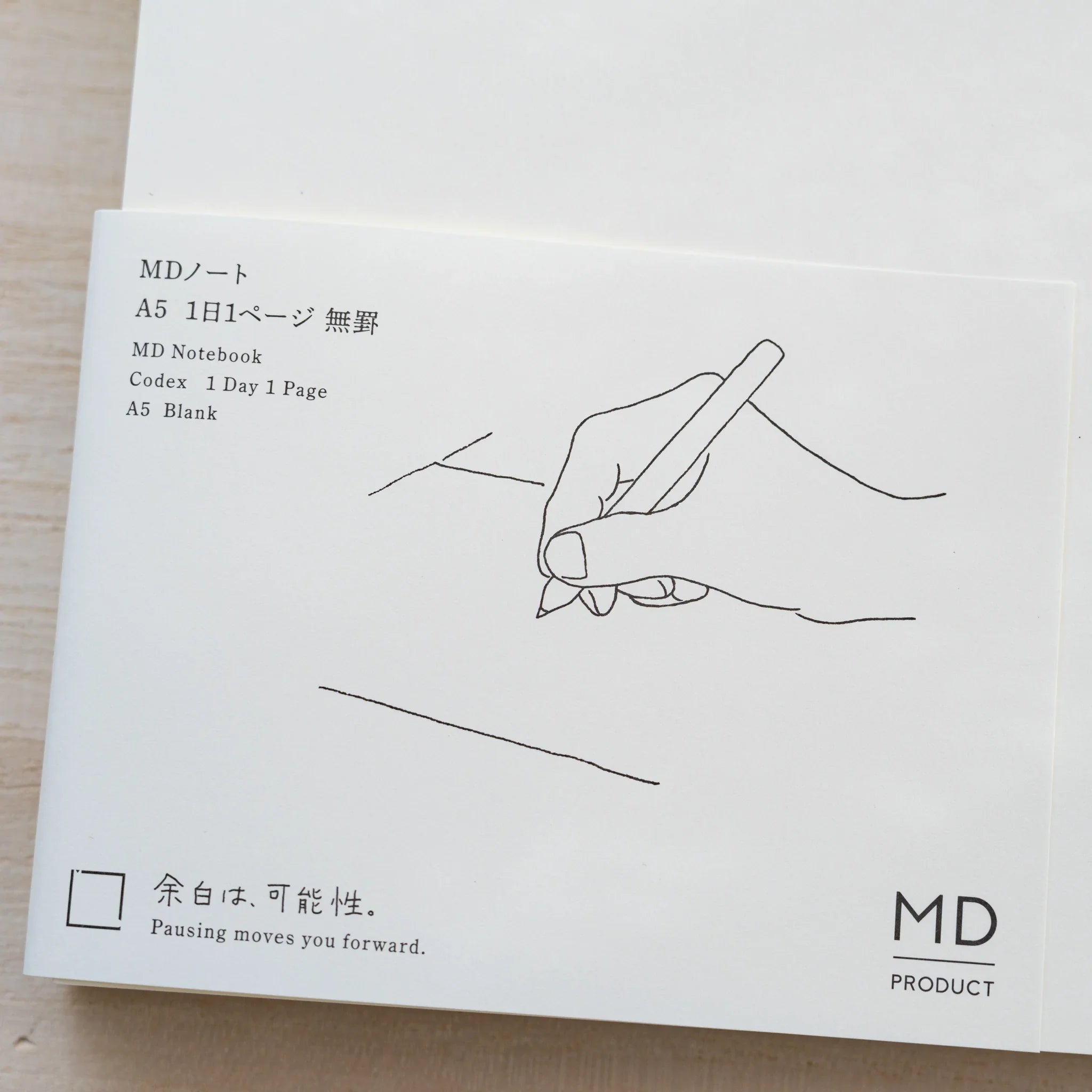 Close-up of Midori MD Notebook paper belly band, line drawing of a hand writing and text MD Notebook 1 Day 1 Page A5 Blank