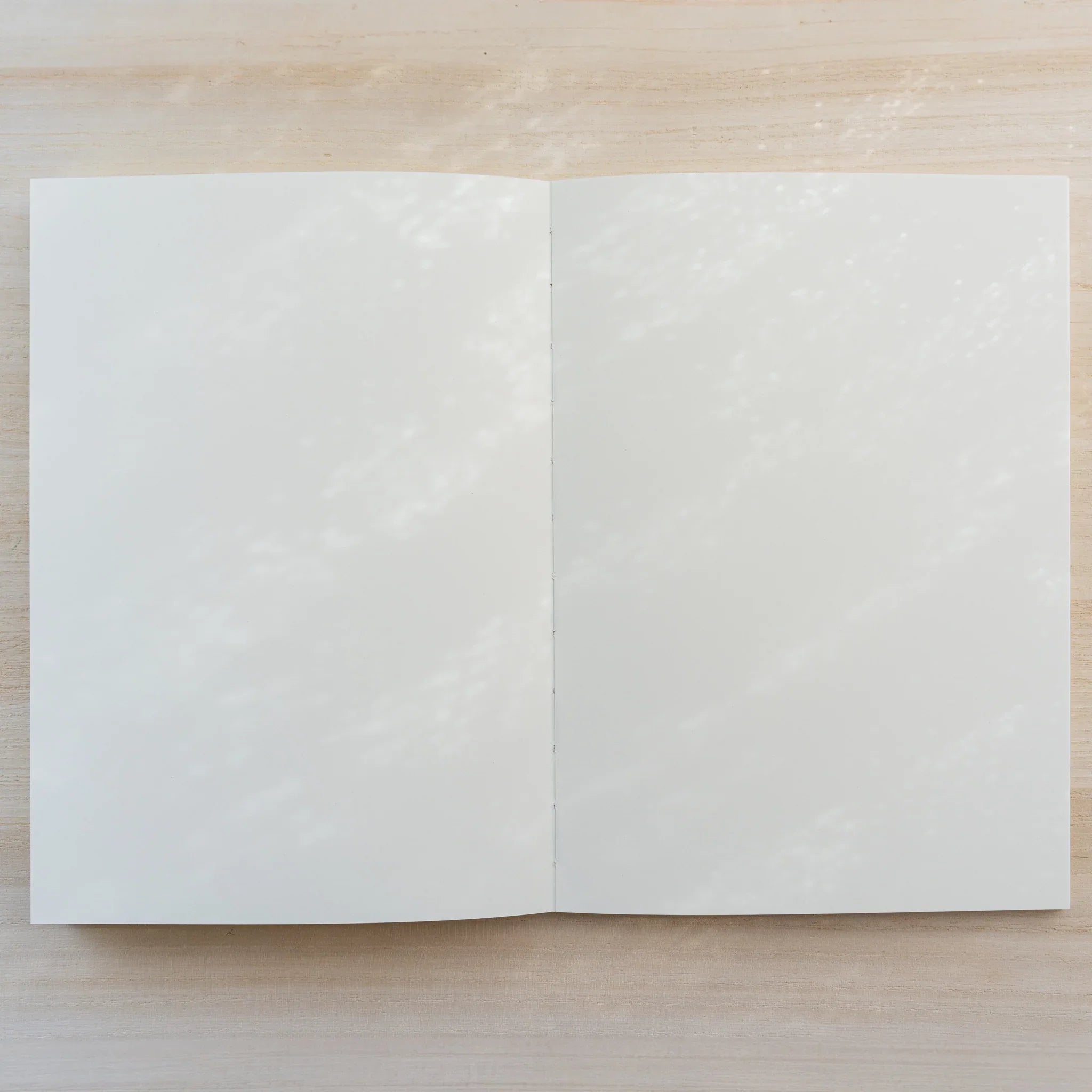 Midori MD Notebook Thick open flat to a blank cream two-page spread with exposed thread stitching at the center spine