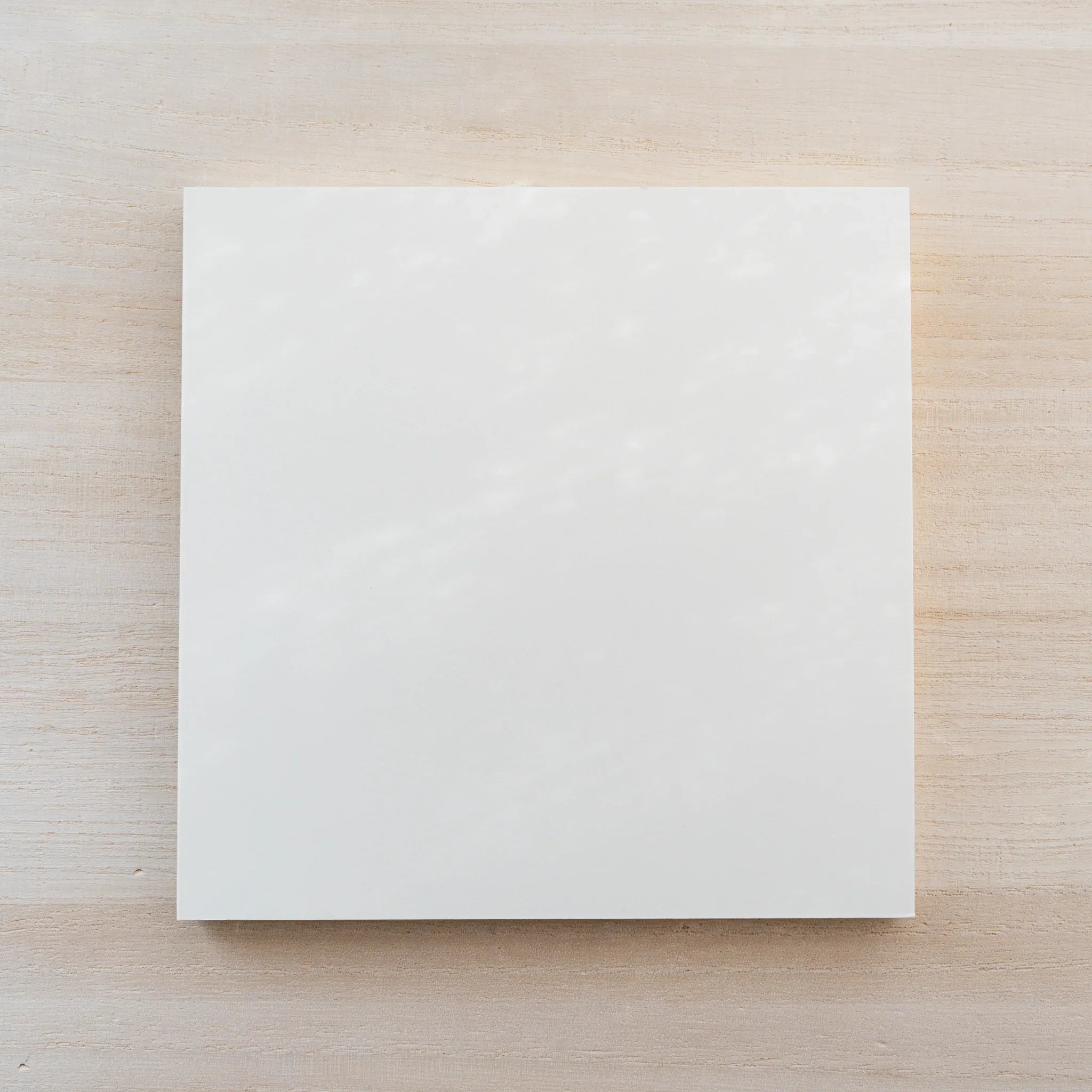 Angled view of the closed square cream MD Notebook Thick Paper A5 Square on a wood surface