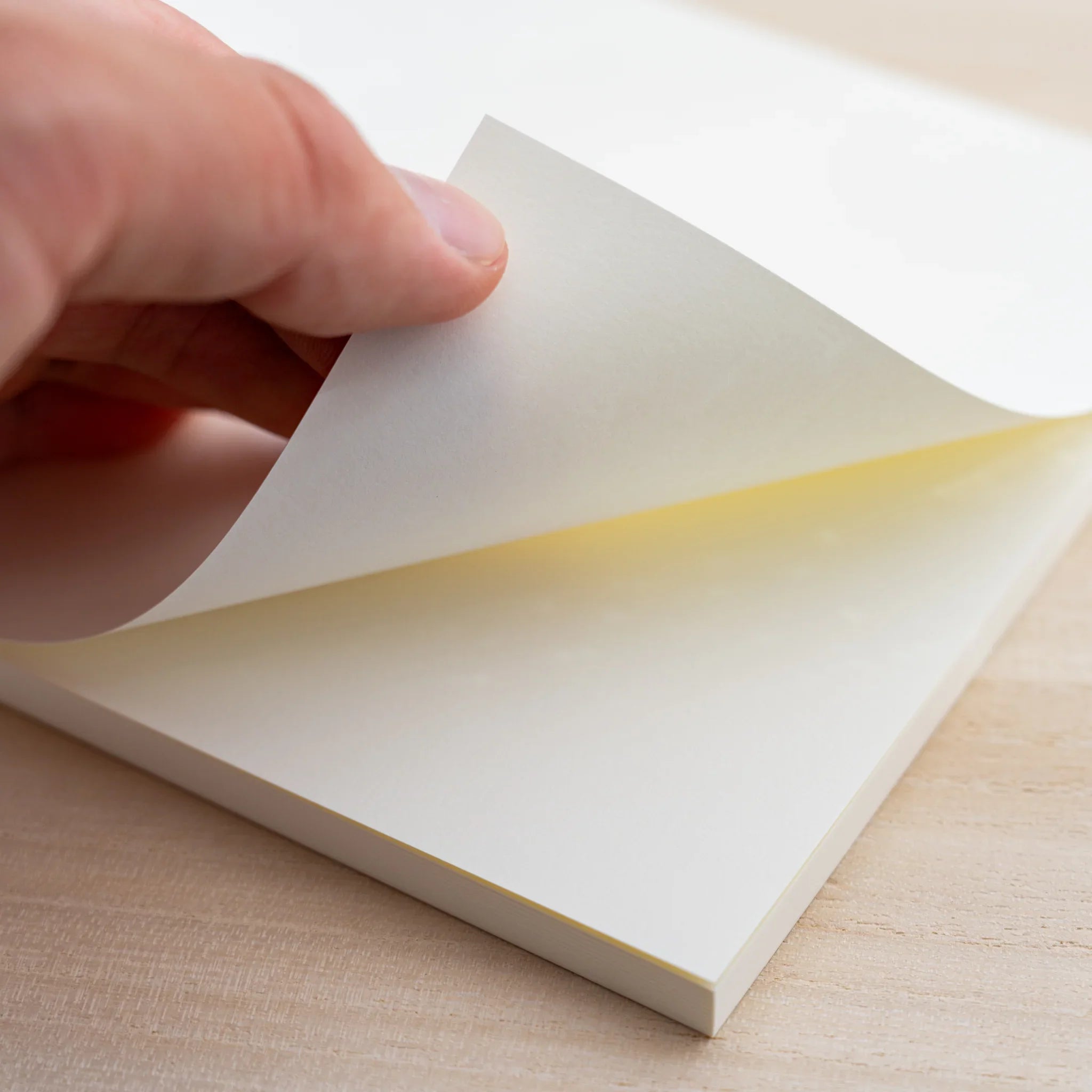 Hand turning a blank cream page of the MD Notebook Thick Paper A5 Square showing the thick paper