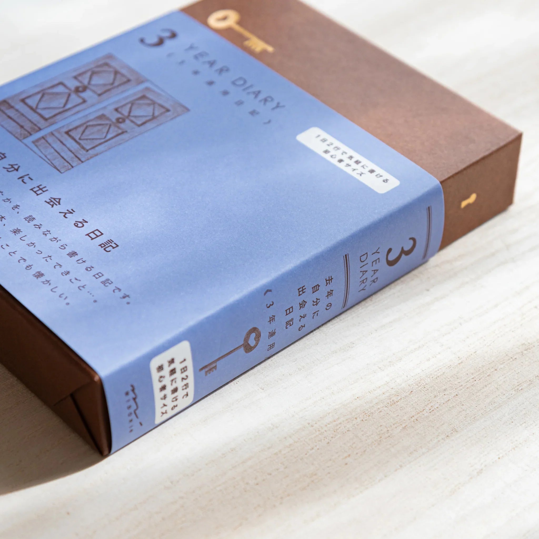 Japanese journal Midori 3-year diary box angled side view showing blue cover with gate design and brown spine.