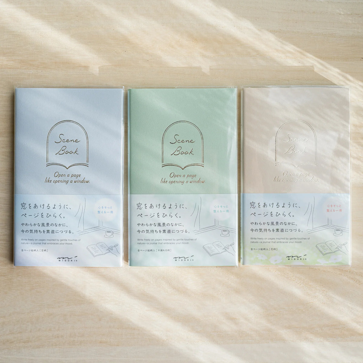 Three Midori Scene Book dot grid journals in Sky blue, Komorebi green and Wildflowers beige covers with paper belly bands