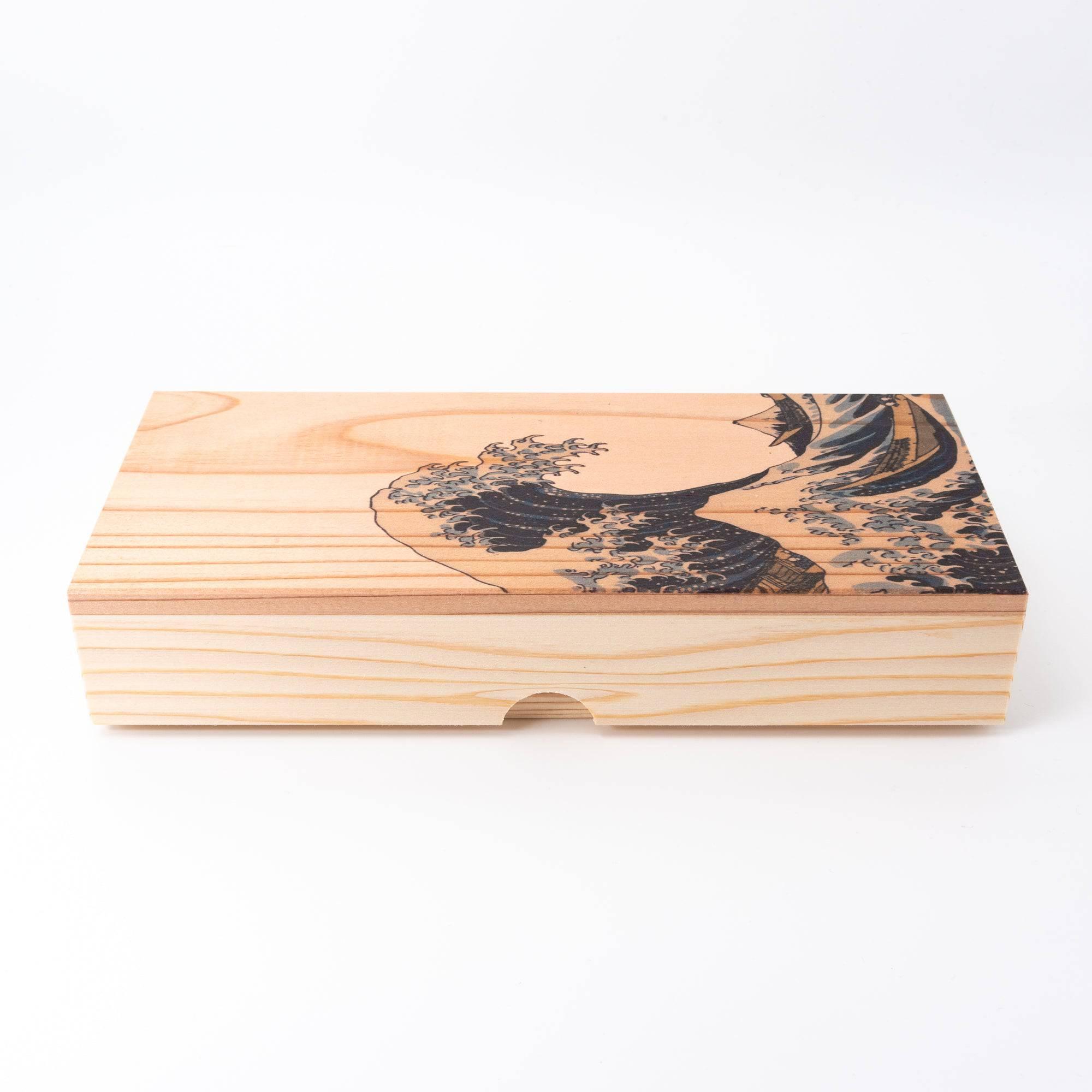 Wooden box with engraved Hokusai’s Great Wave design, showcasing craftsmanship and natural wood texture. (88 characters)