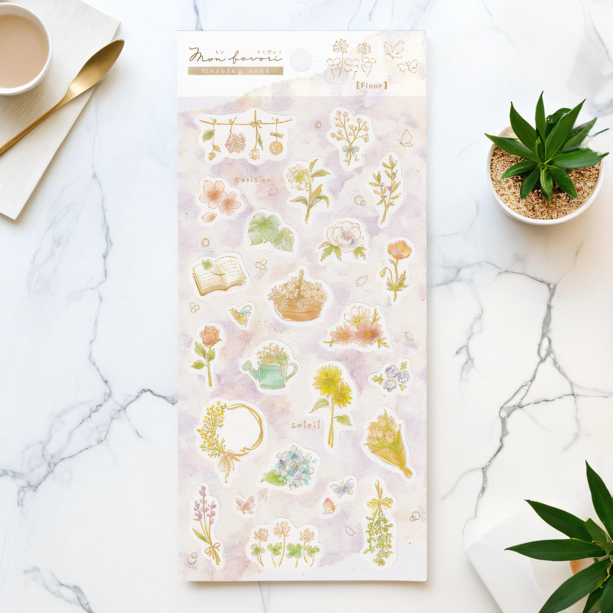 A Japanese washi sticker sheet with delicate floral designs—roses, daisies, hydrangeas, a wreath, a watering can, a book, and butterflies—on a soft pastel background. Elegant and charming.