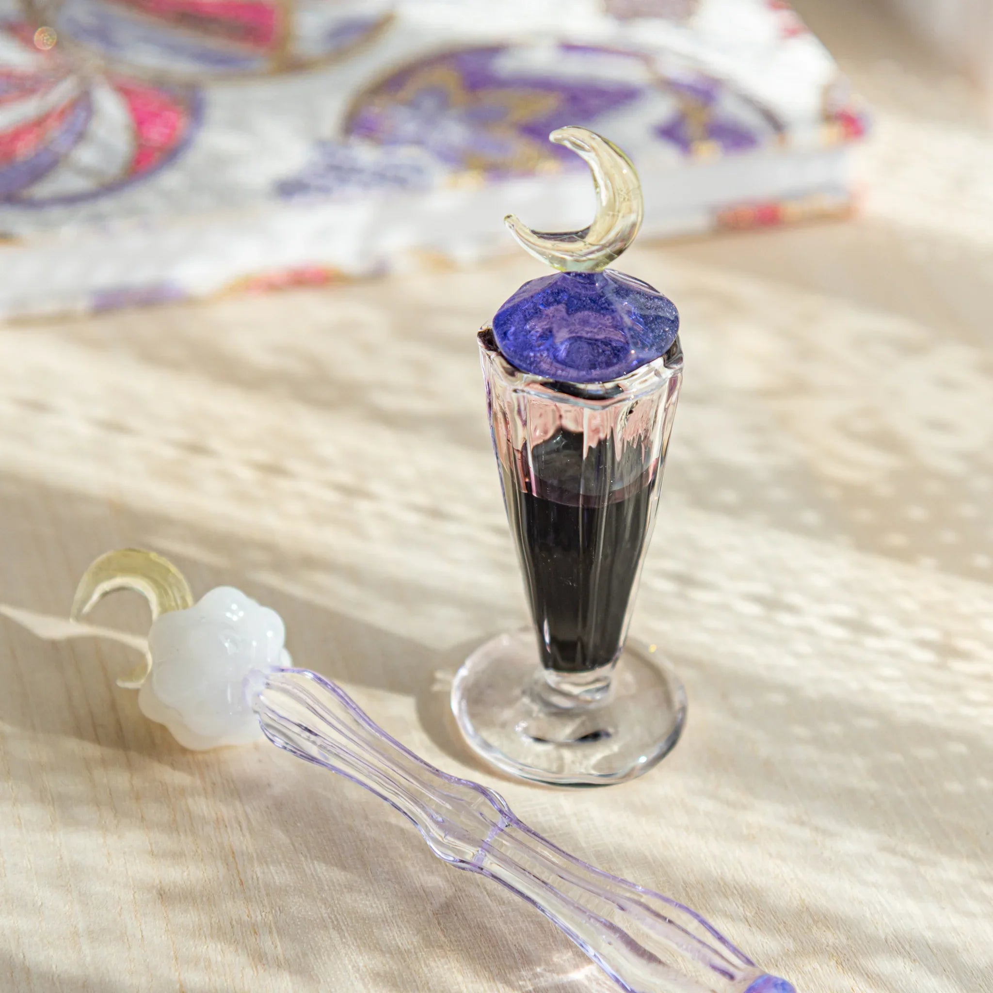 Japanese glass ink well with crescent moon lid, paired with a glass dip pen, filled with ink to create an elegant writing scene.