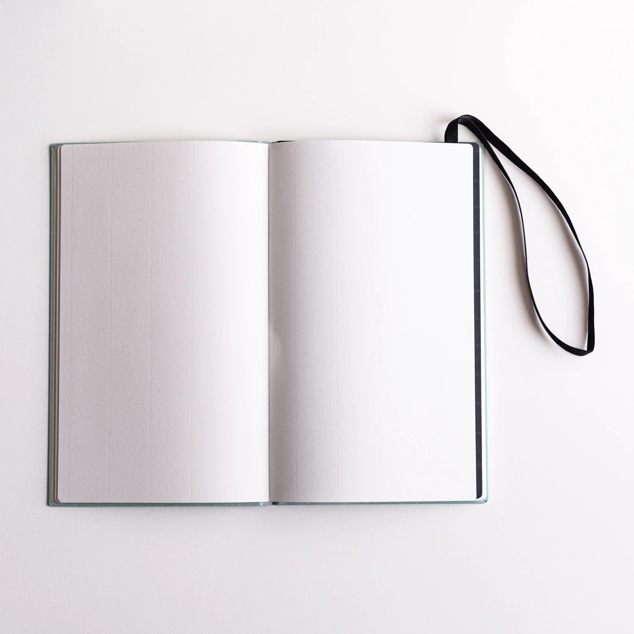 Open blank notebook with Dressco Sebiro Navy Blue bookmark band inserted, elastic strap extending to the side to mark pages.