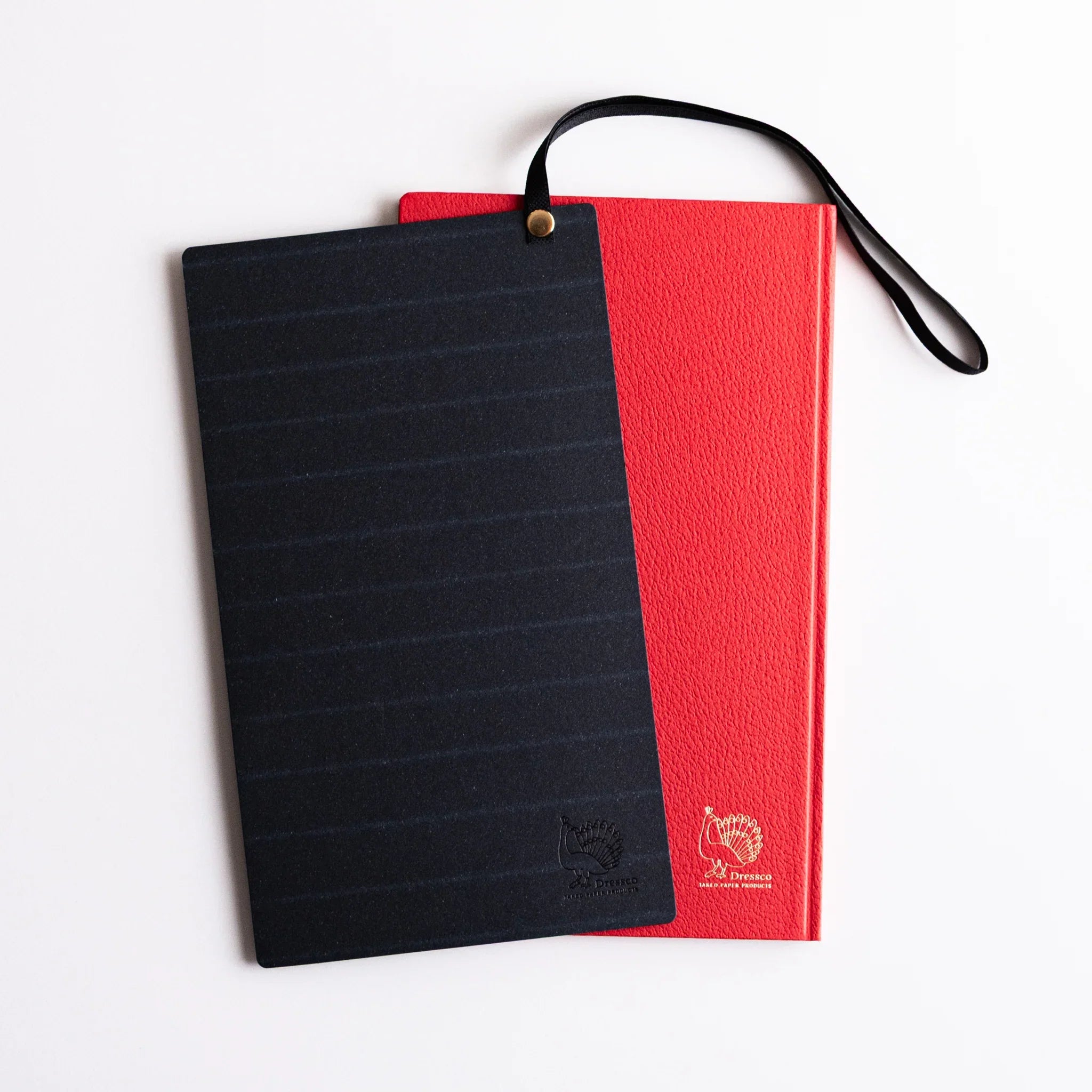 Dressco Sebiro Navy Blue bookmark band placed on red notebook, showing striped texture, embossed logo and elastic strap with gold stud.