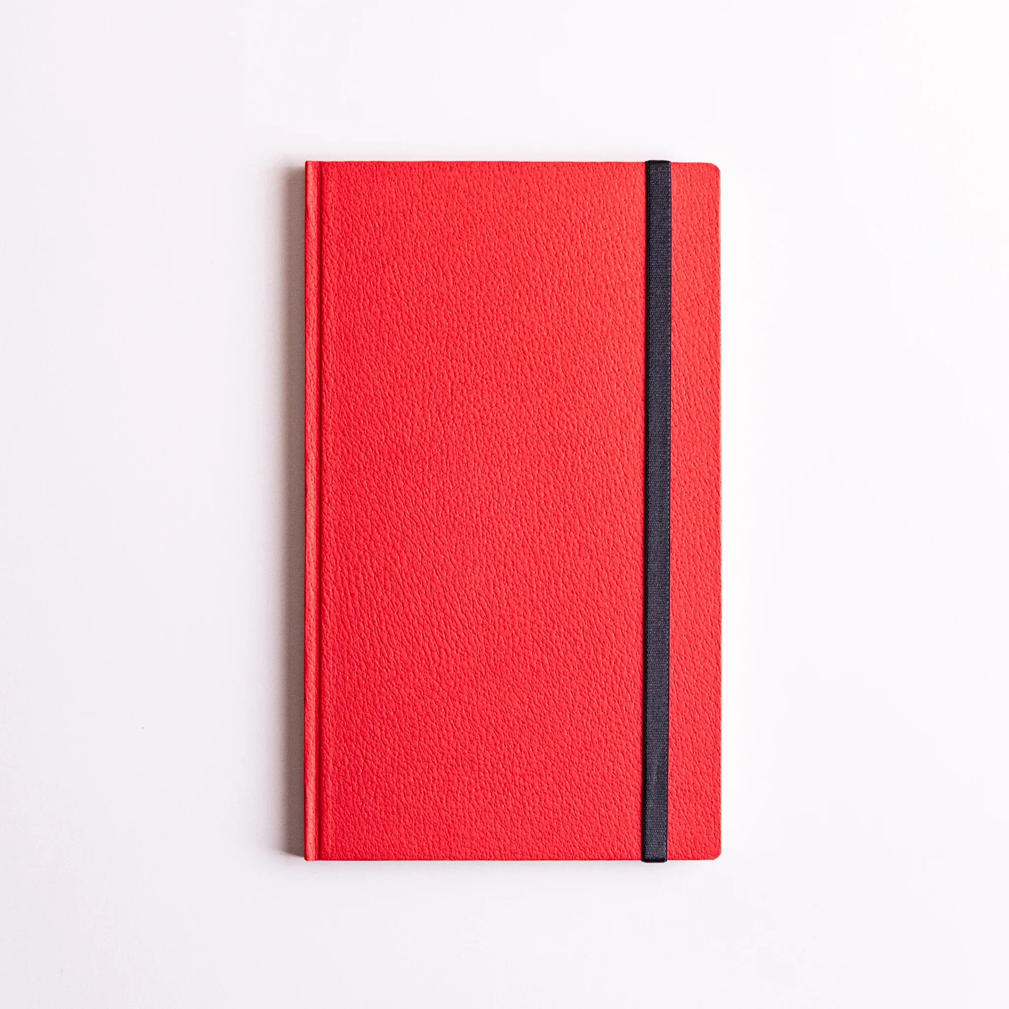 Closed red notebook with Dressco Sebiro Navy Blue bookmark band strapped vertically along cover for secure closure.