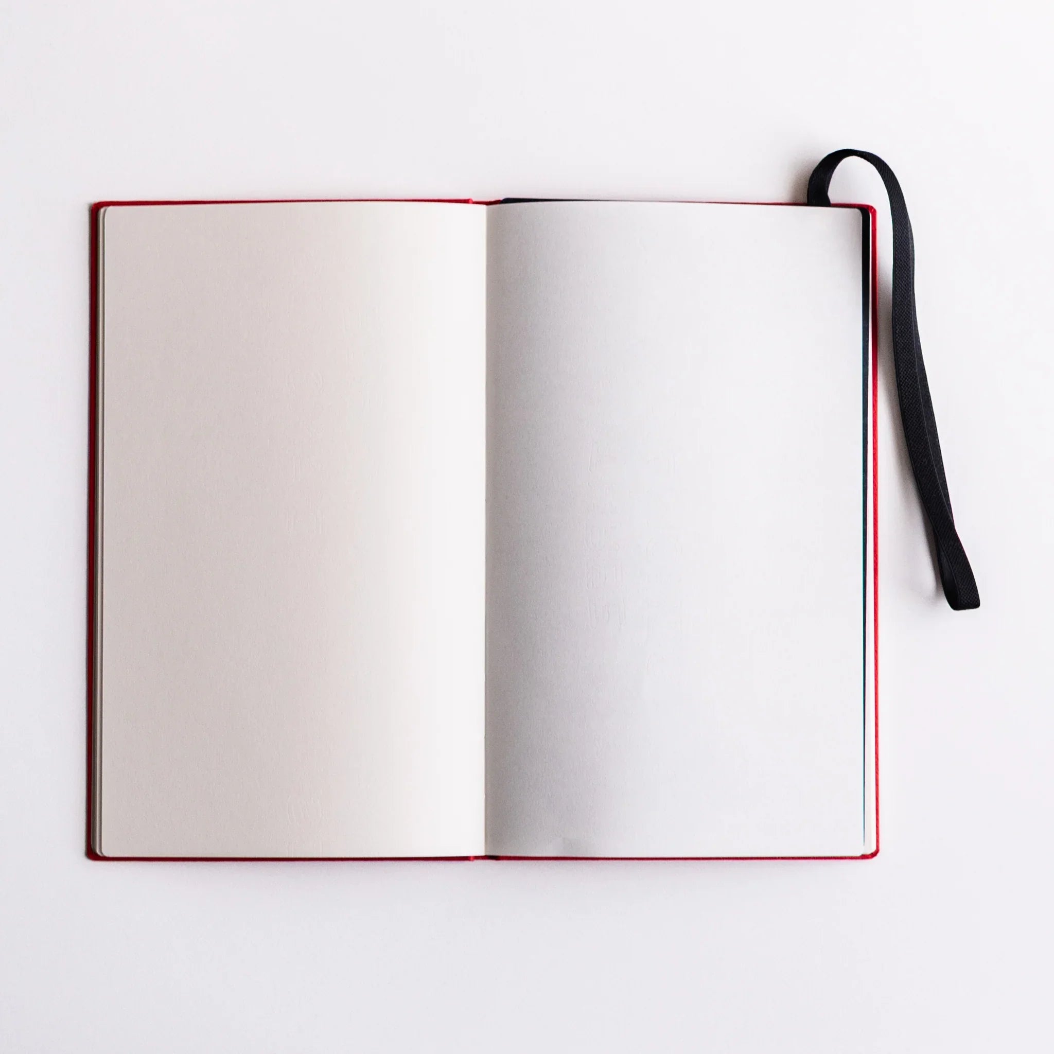 Open blank notebook with Dressco Sebiro Navy Blue bookmark band inserted; elastic strap extending from top corner for closure and bookmarking.