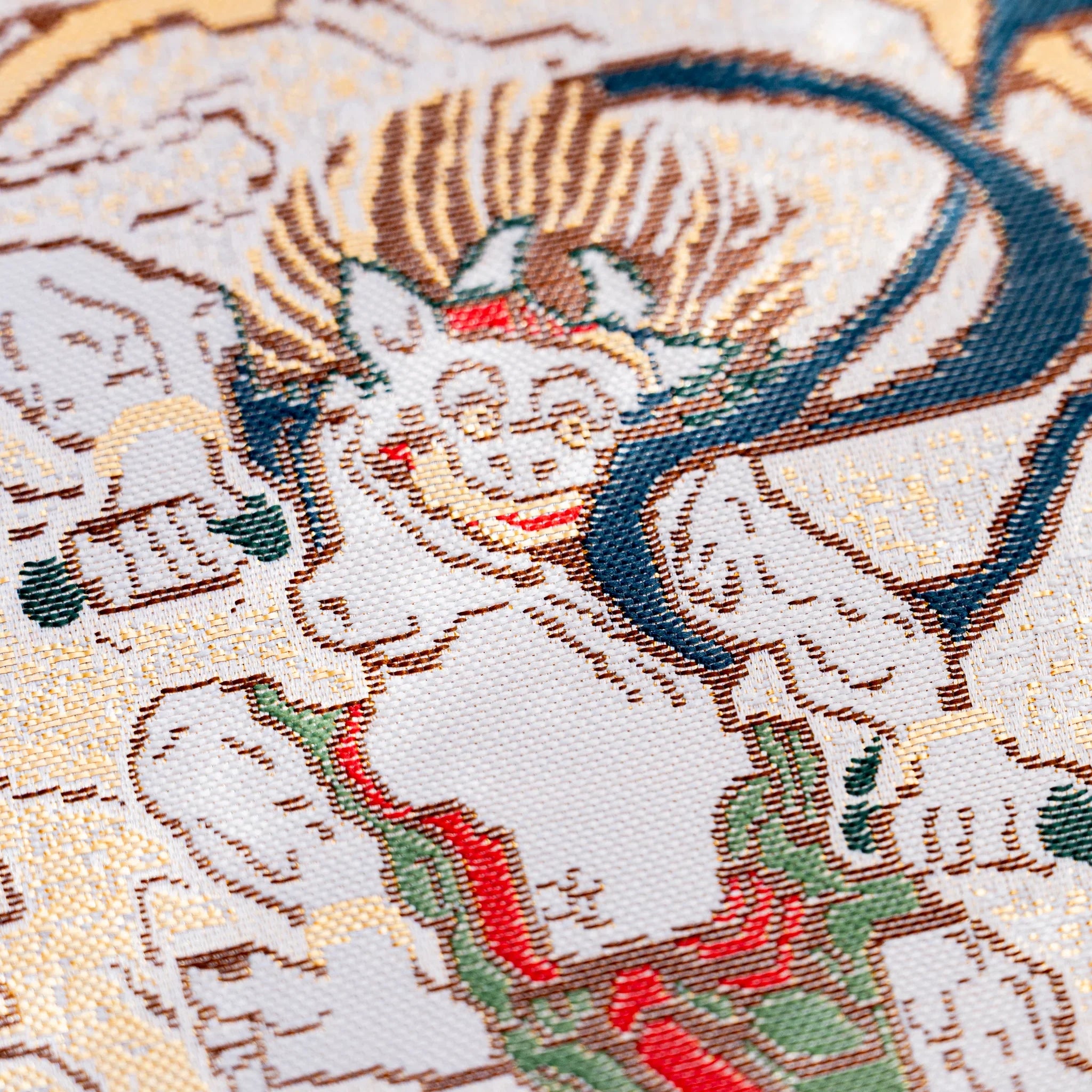Close-up of woven textile showing pale thunder god Raijin with horns and surrounding drums